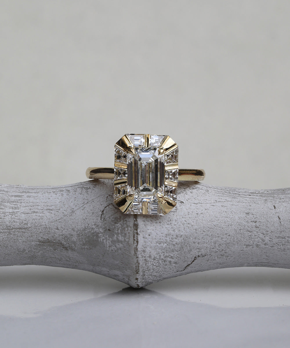 Alternative maximalist emerald cut engagement ring with a halo of hand-cut diamonds