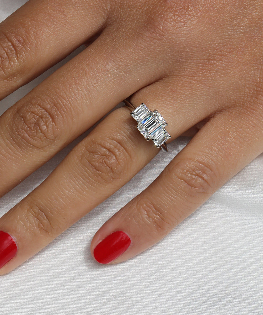 Emerald cut trilogy three stone engagement ring in a sleek platinum setting. Made in the UK