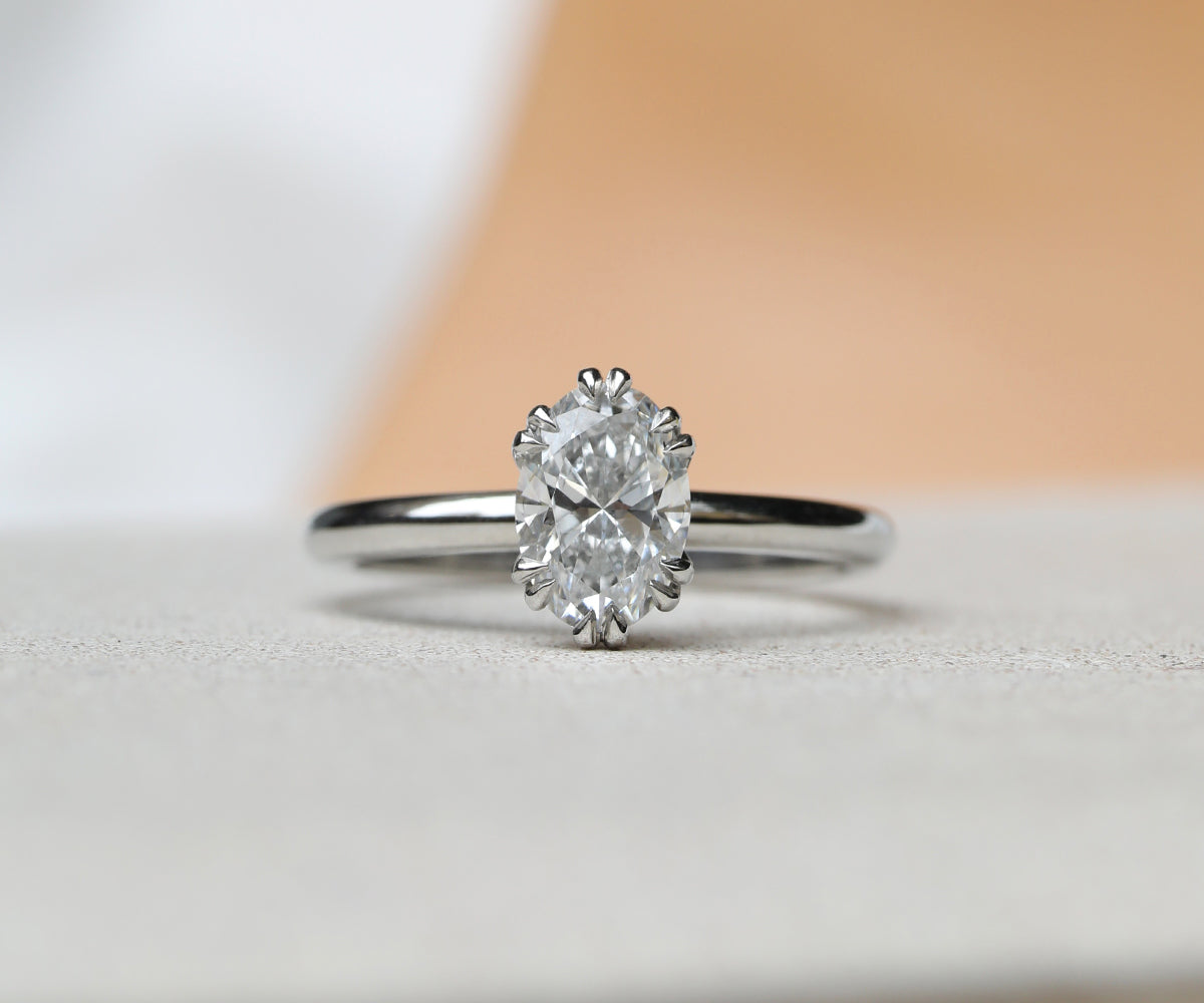Mid century inspired engagement ring with vintage details of double claws around this classic oval cut diamond.