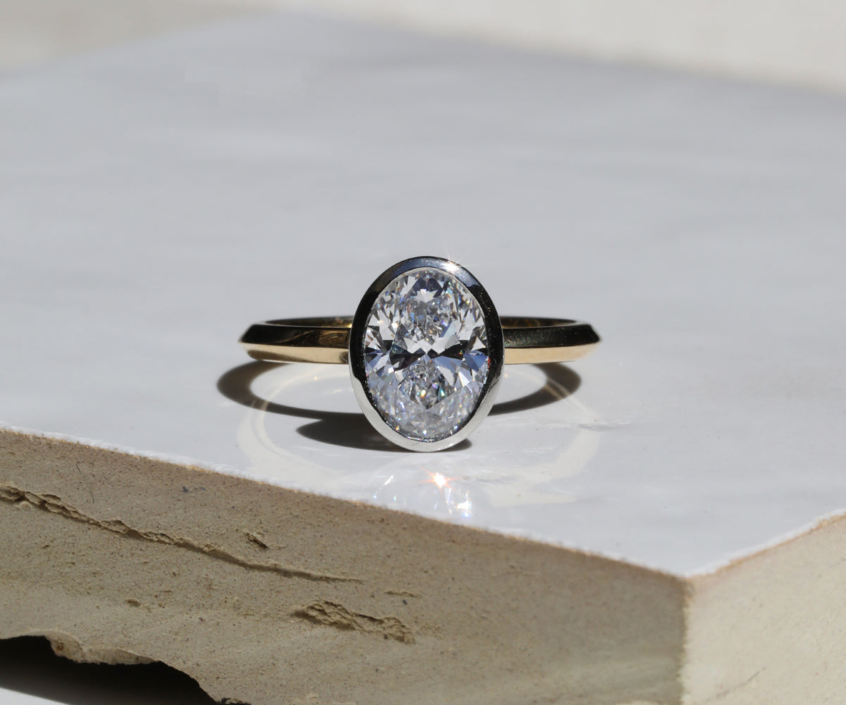 Split platinum and gold bezel set oval cut engagement ring.