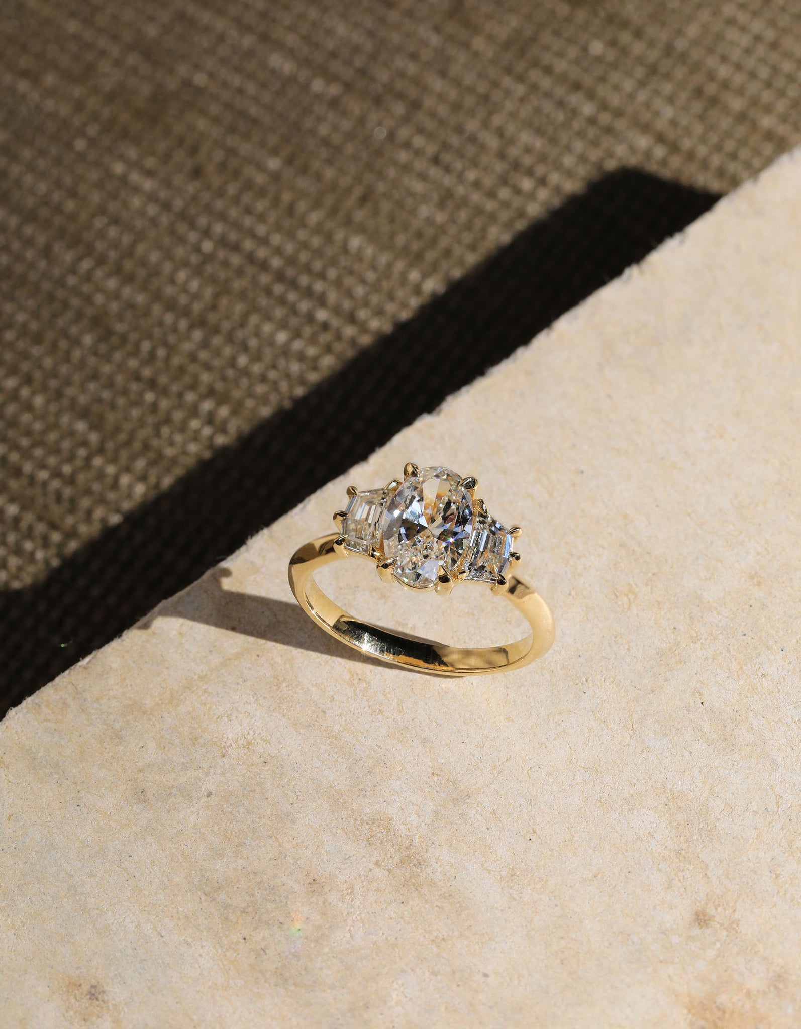 Oval diamond trilogy engagement ring with geometric Epaulette Cut diamond sidestones.