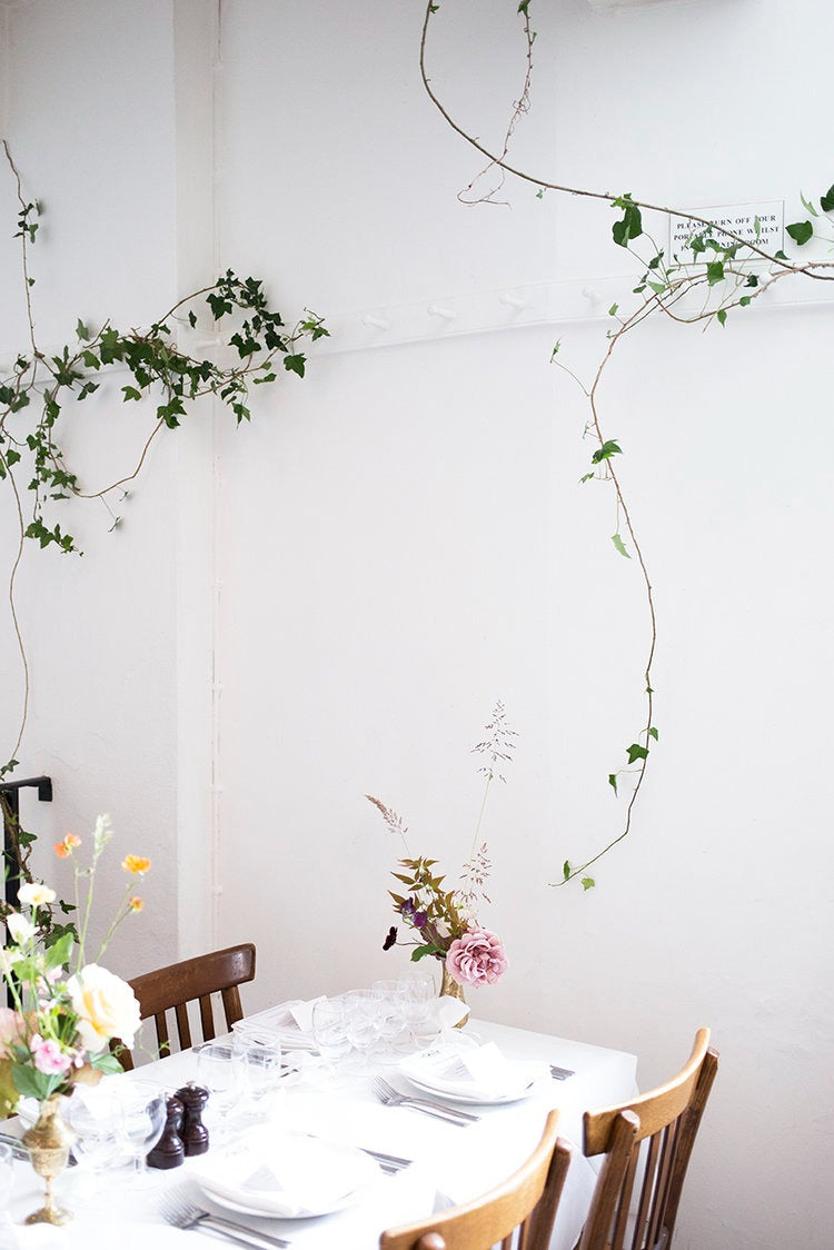 A delicate arrangement of vines and flowers across the wedding table by Aesme Studio.