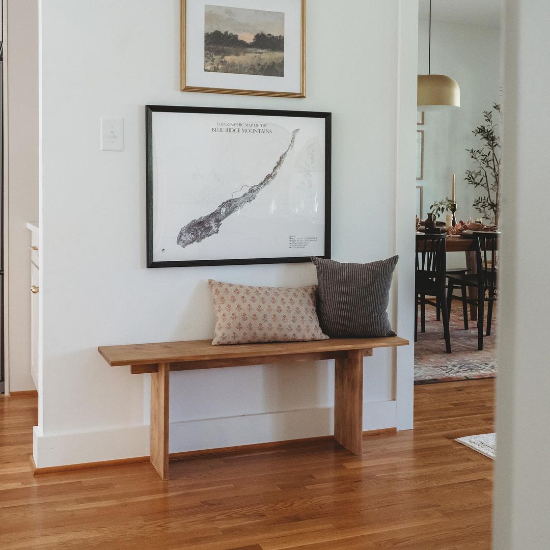 wooden bench below a framed piece of art