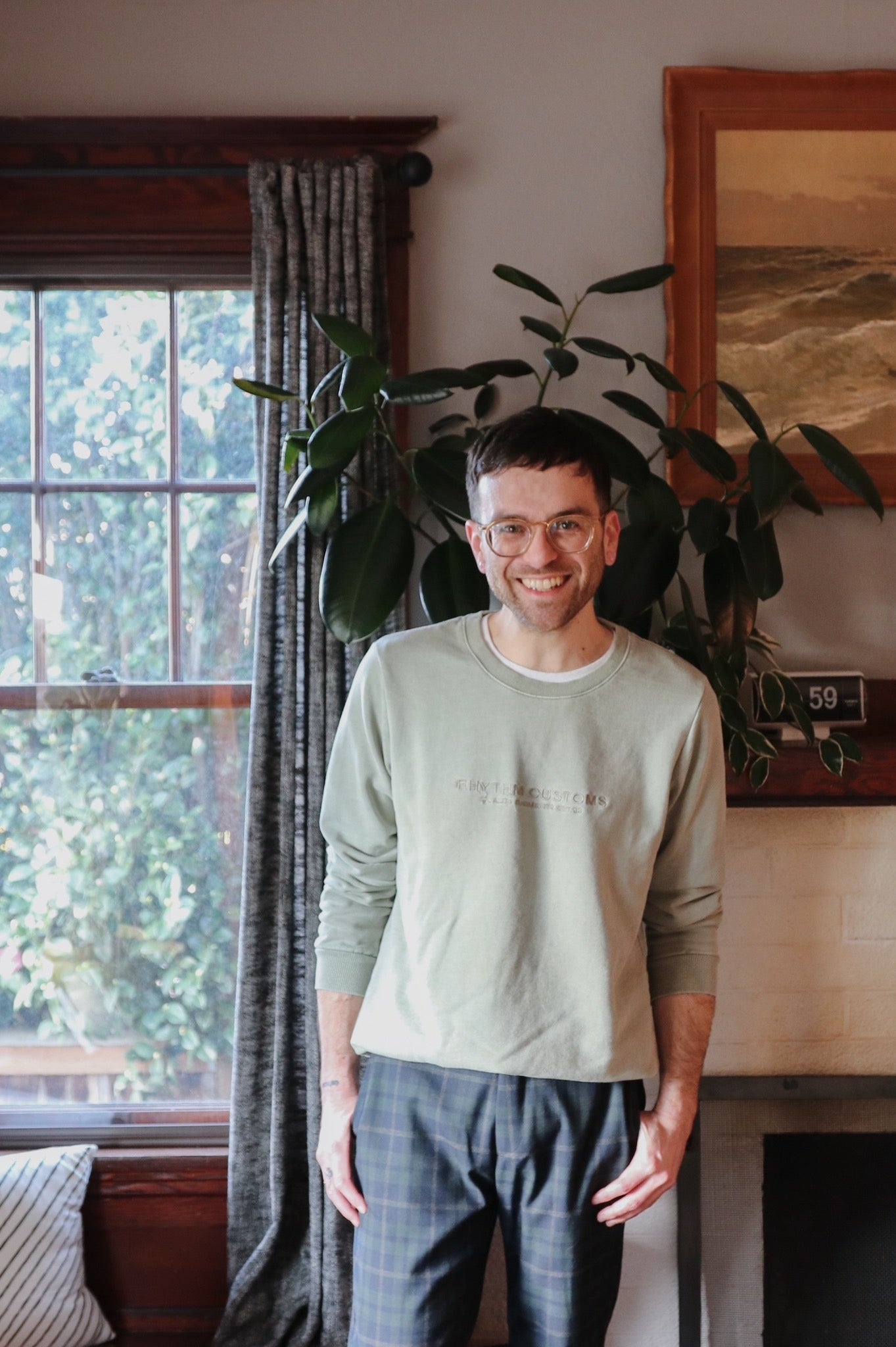 person smiling in front of a window and plant