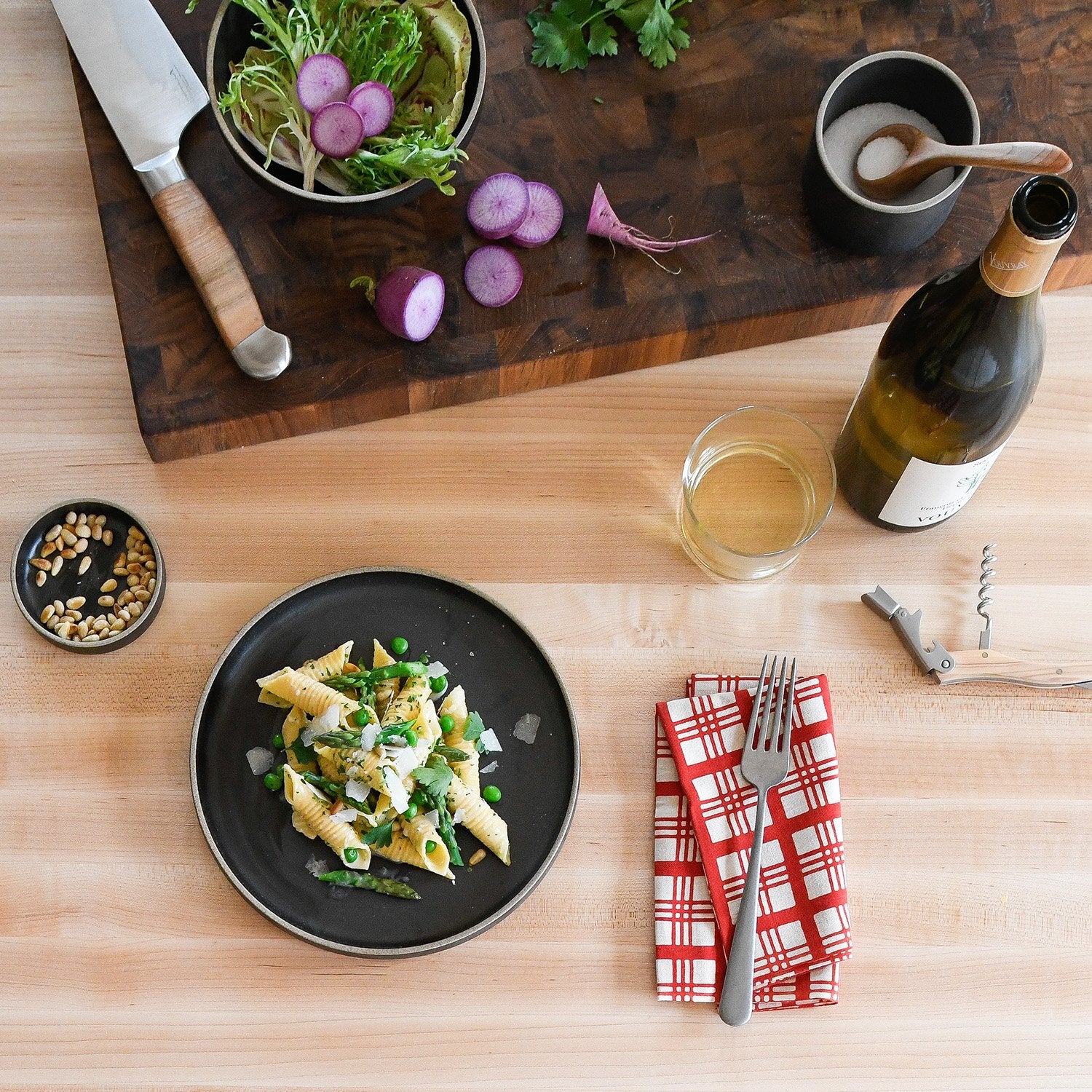 table with cutting board and a knife and a black bowl of food