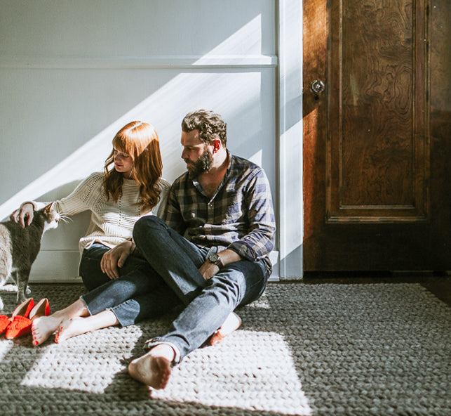 man and woman sitting on the floor petting a cat