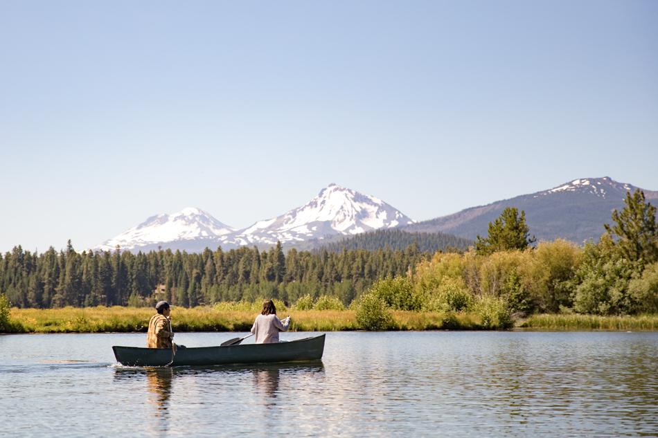 couple of people in a canoe on a lake with mountains in the background