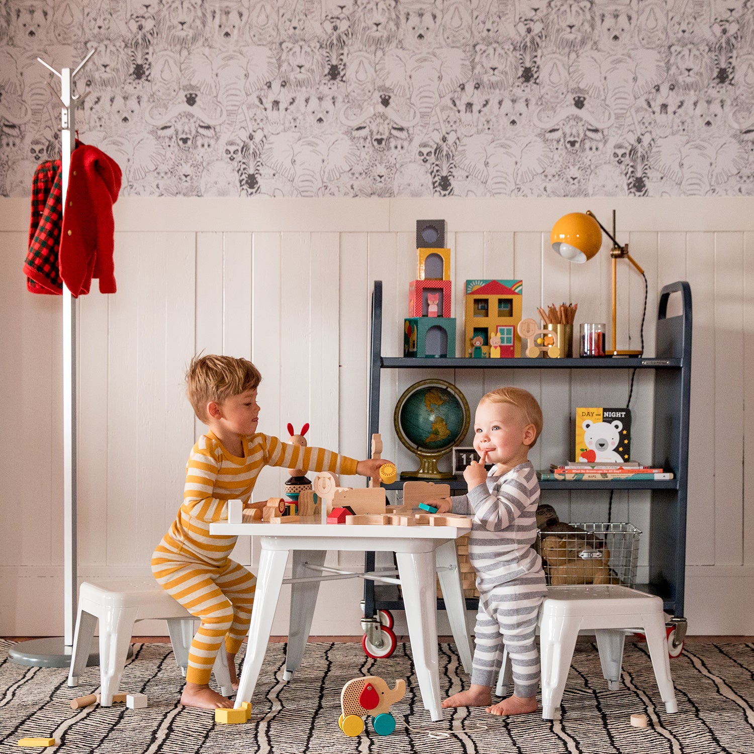 couple of children sitting at a table with toys on it