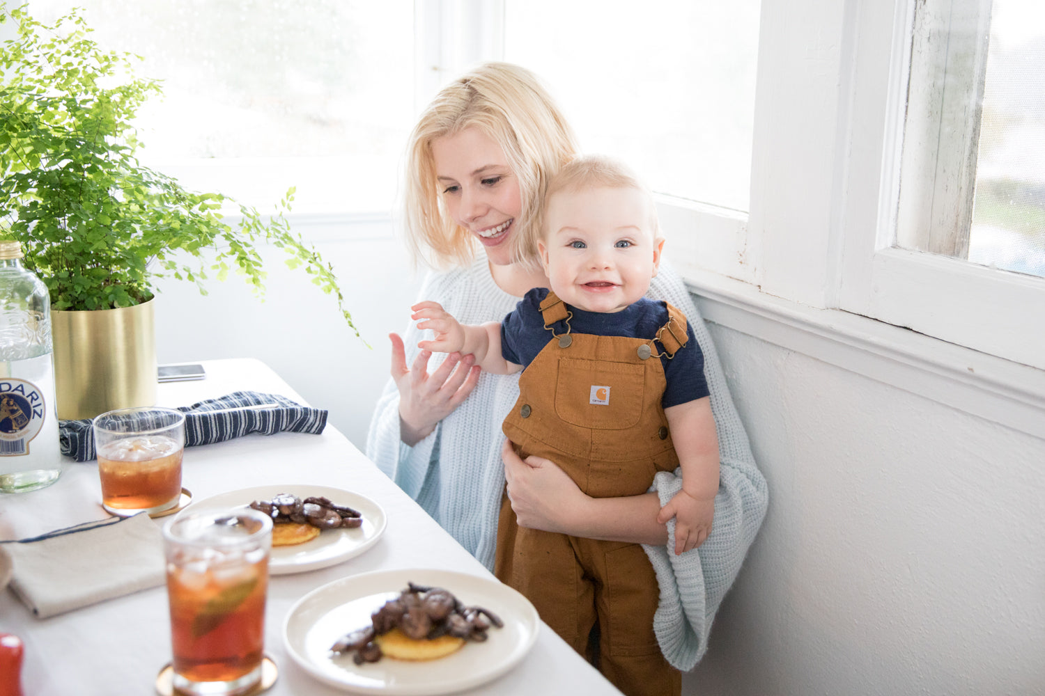 person and a child sitting at a table with food and drinks