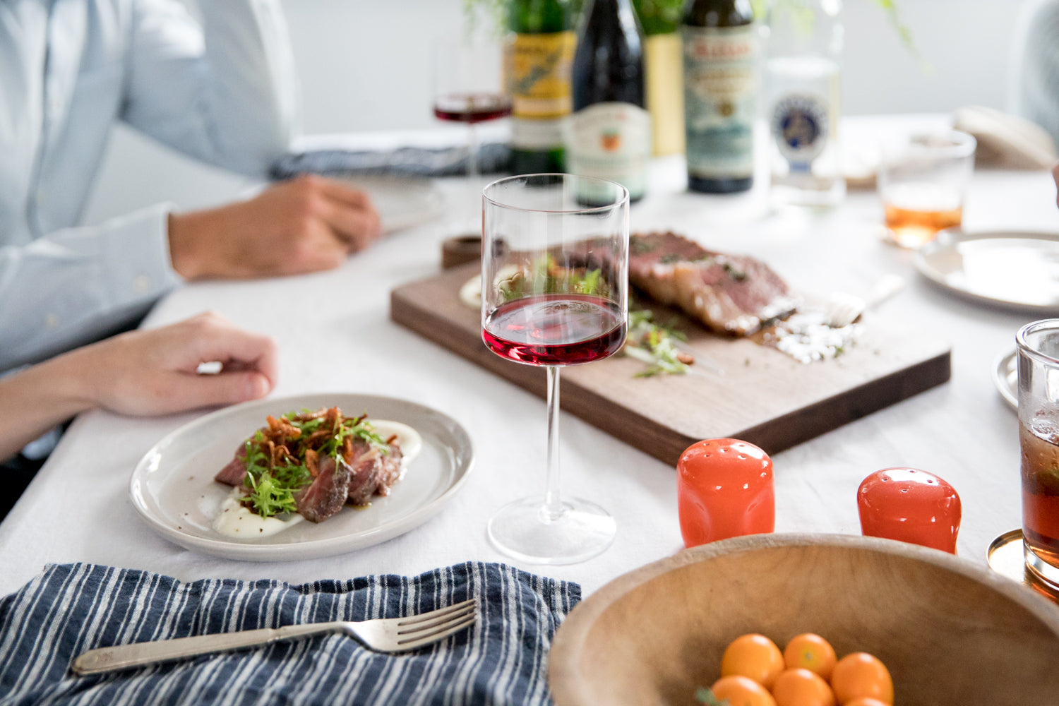 person sitting at a table with food and wine