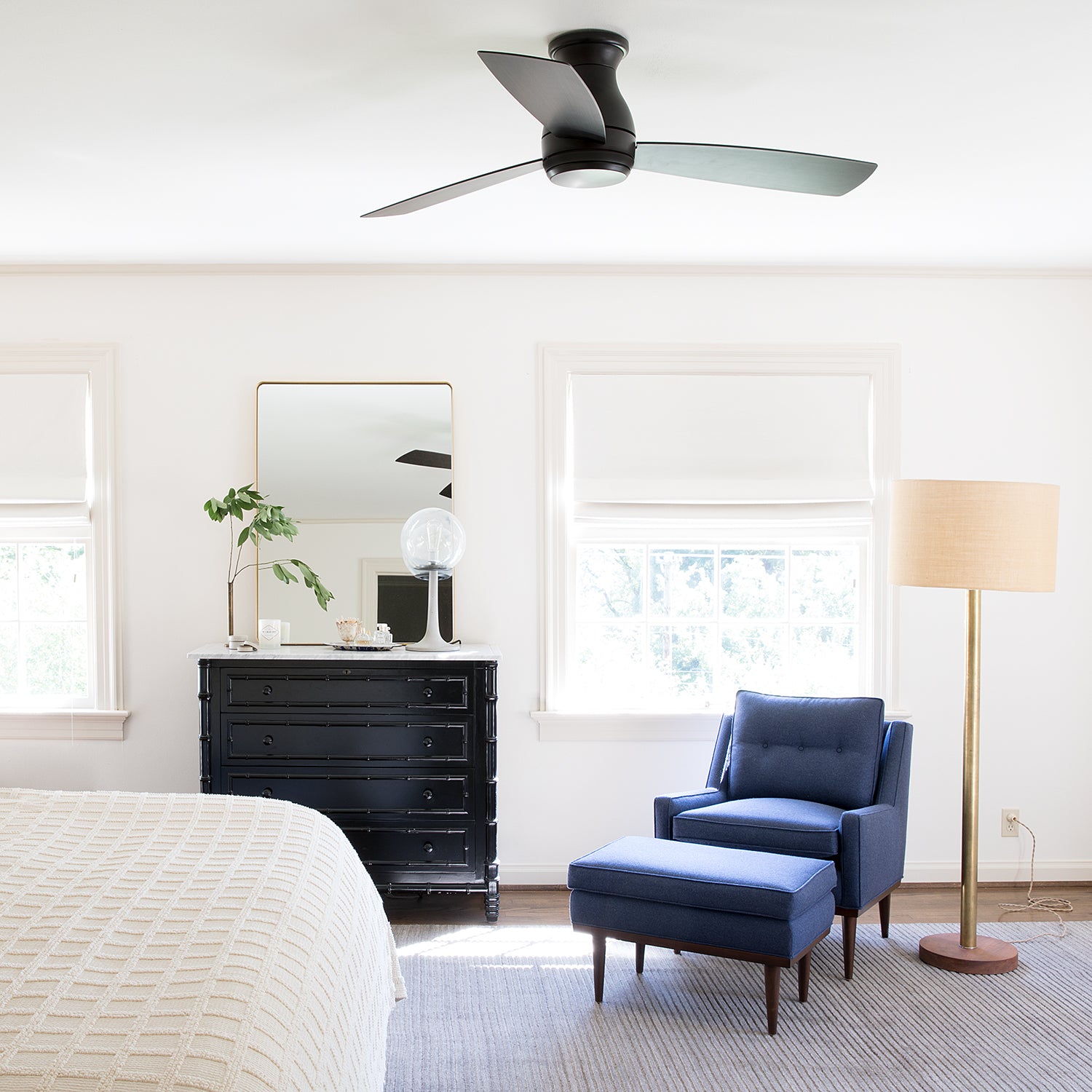 bedroom with a blue chair and a ceiling fan and black dresser