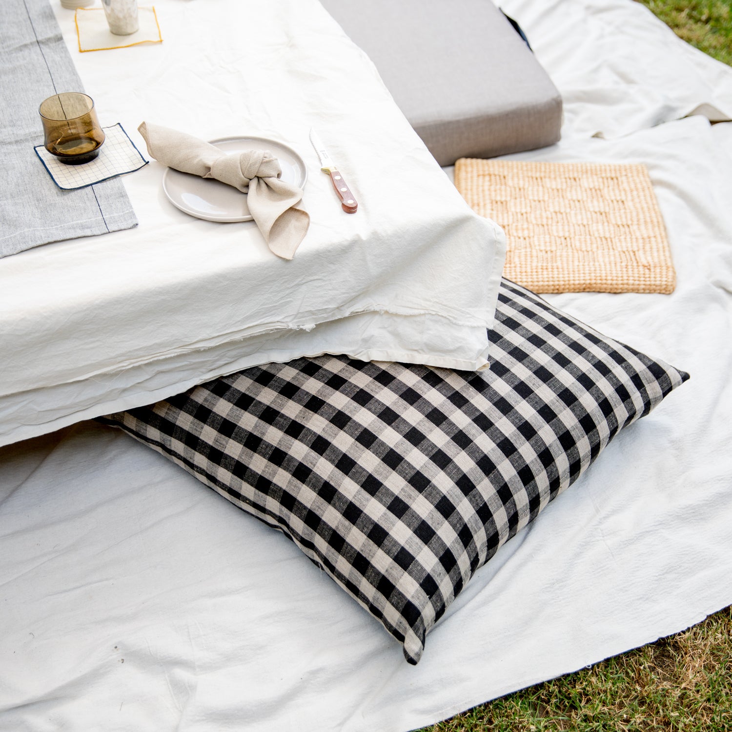 outdoor table on picnic blanket with a black and white gingham pillow