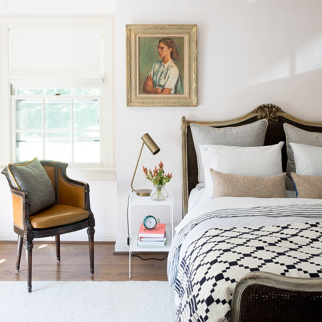 bedroom with a bed and a chair and a black and white bed spread