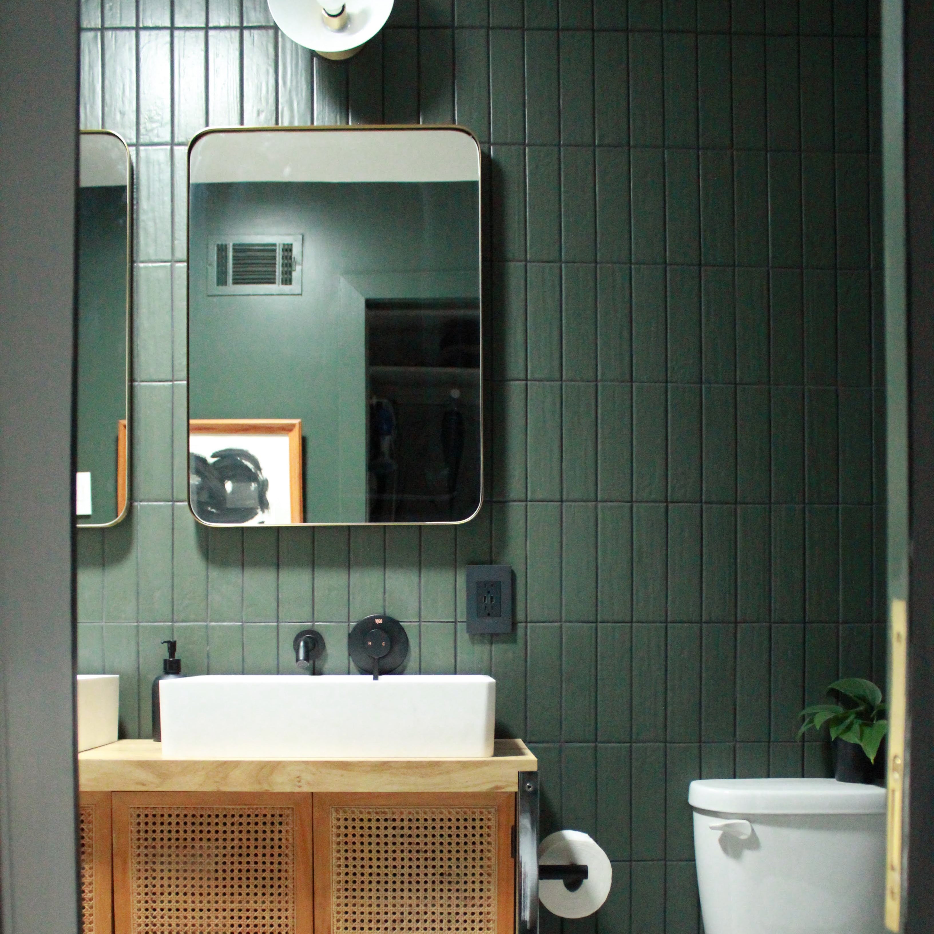 bathroom with a mirror and a sink and green tiled wall