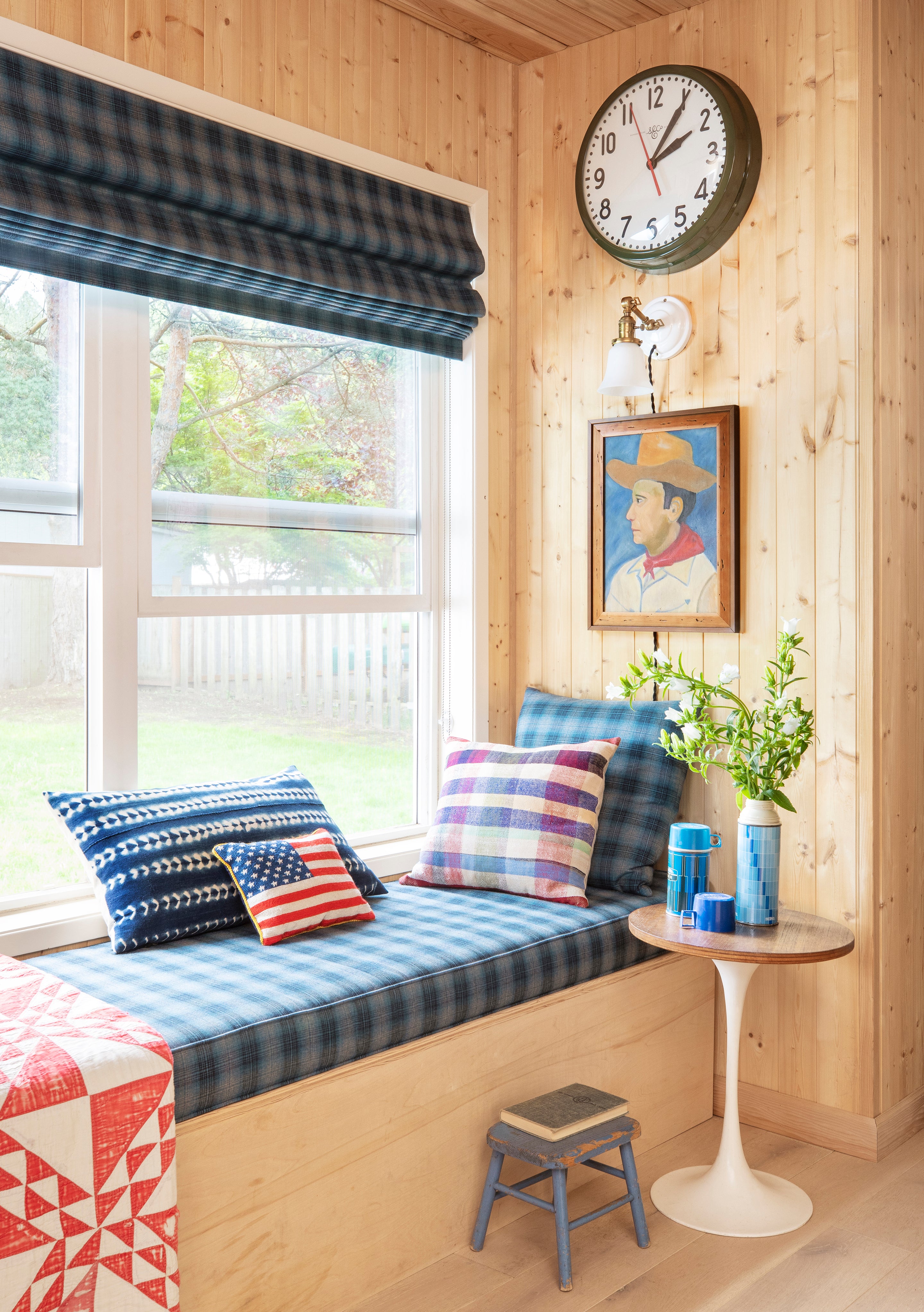 window bench with blue checkered cushions and round table and clock on the wall