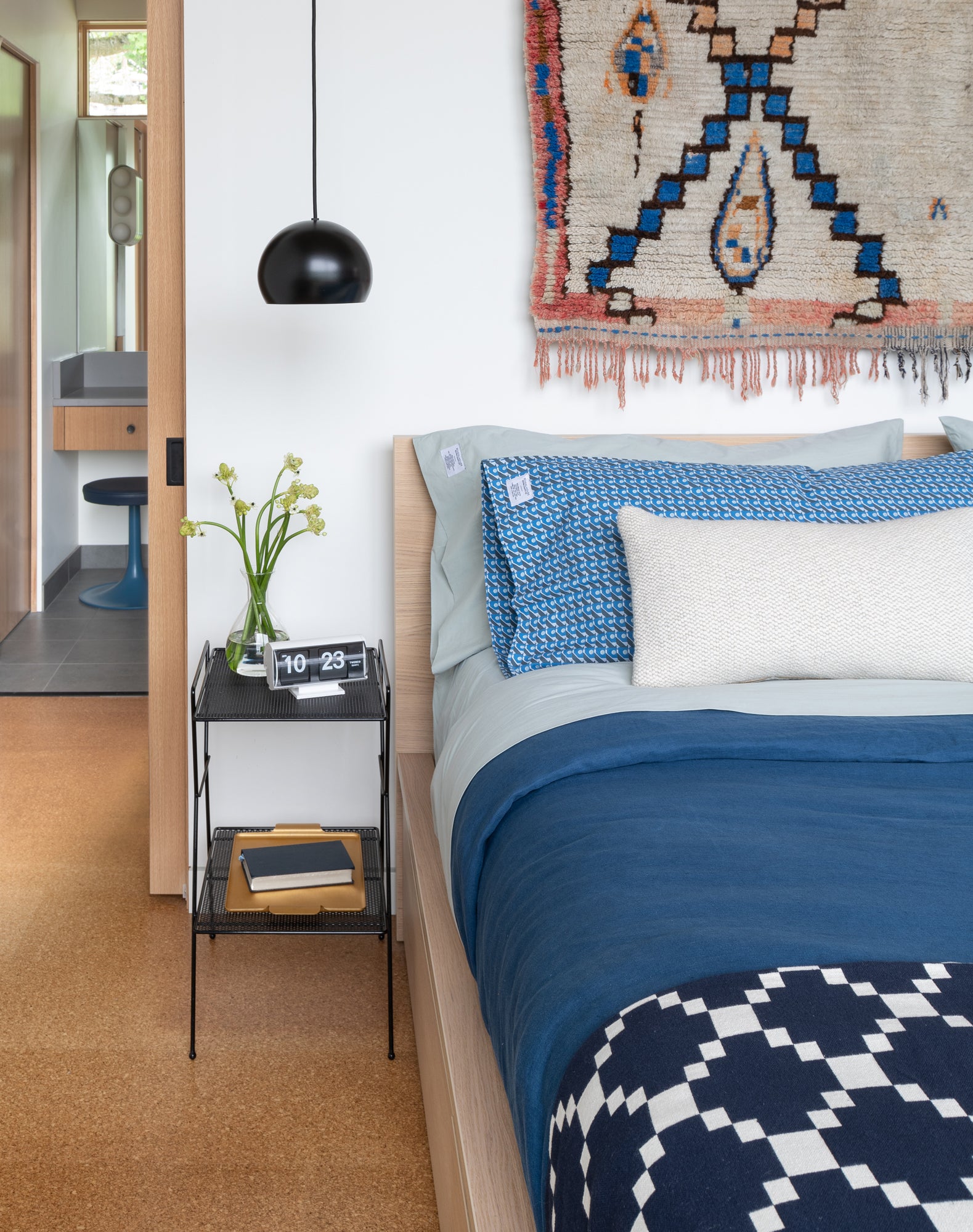 bed with a blue and white bed spread and a plant on the side