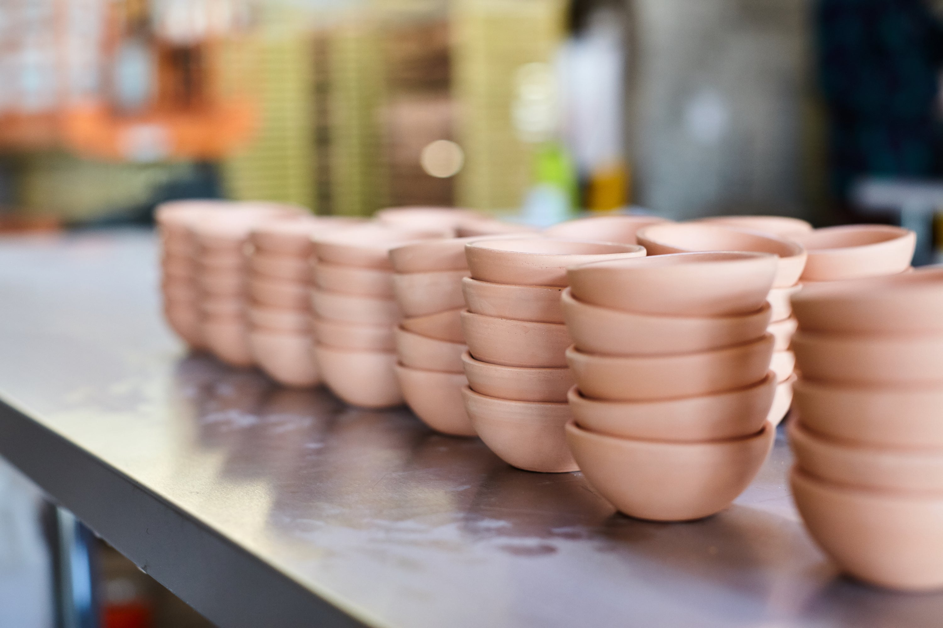 Stacks of unglazed East Fork bowls in a row on a metal table