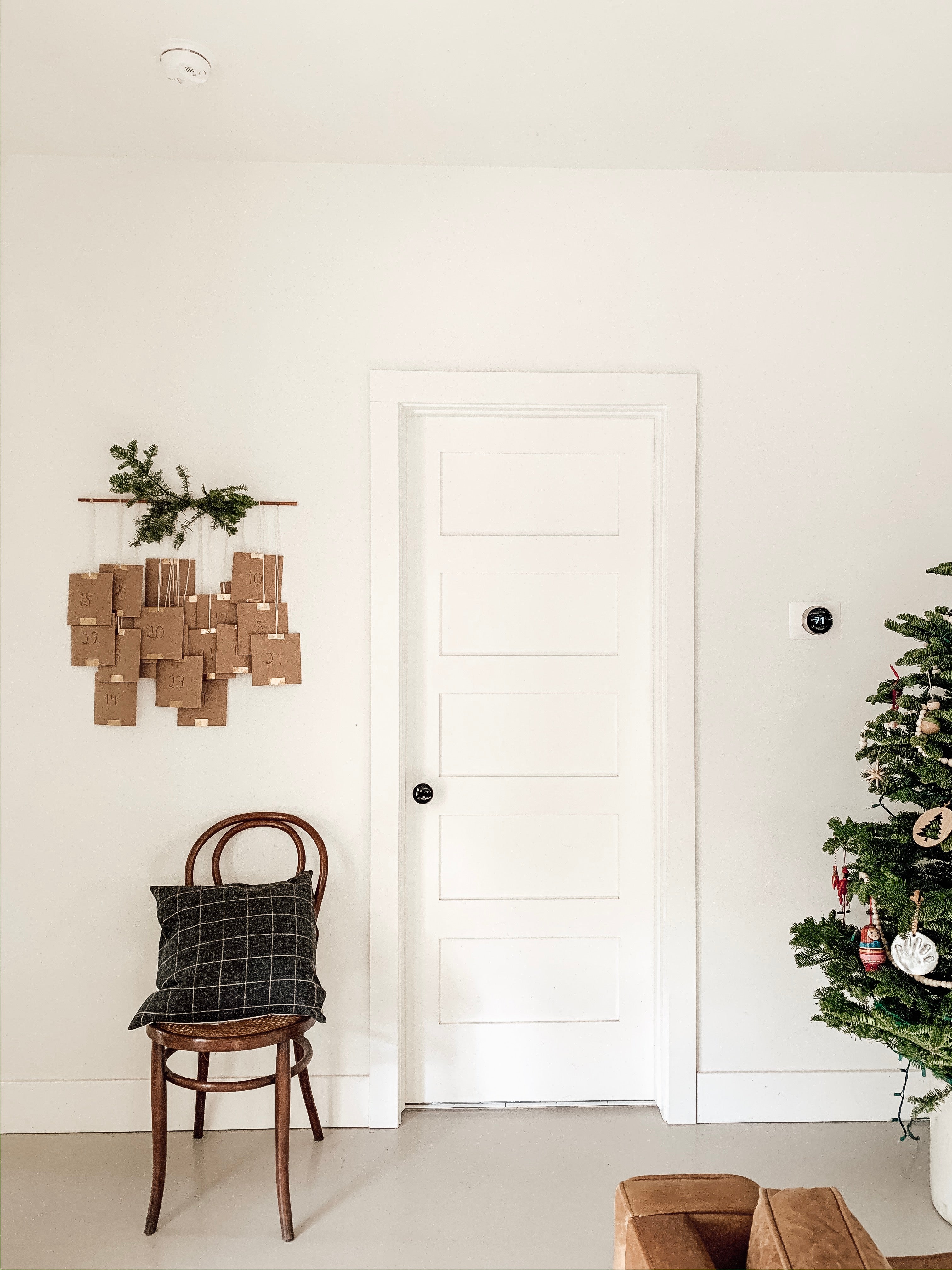 chair with a pillow next to a white door and below an advent calendar