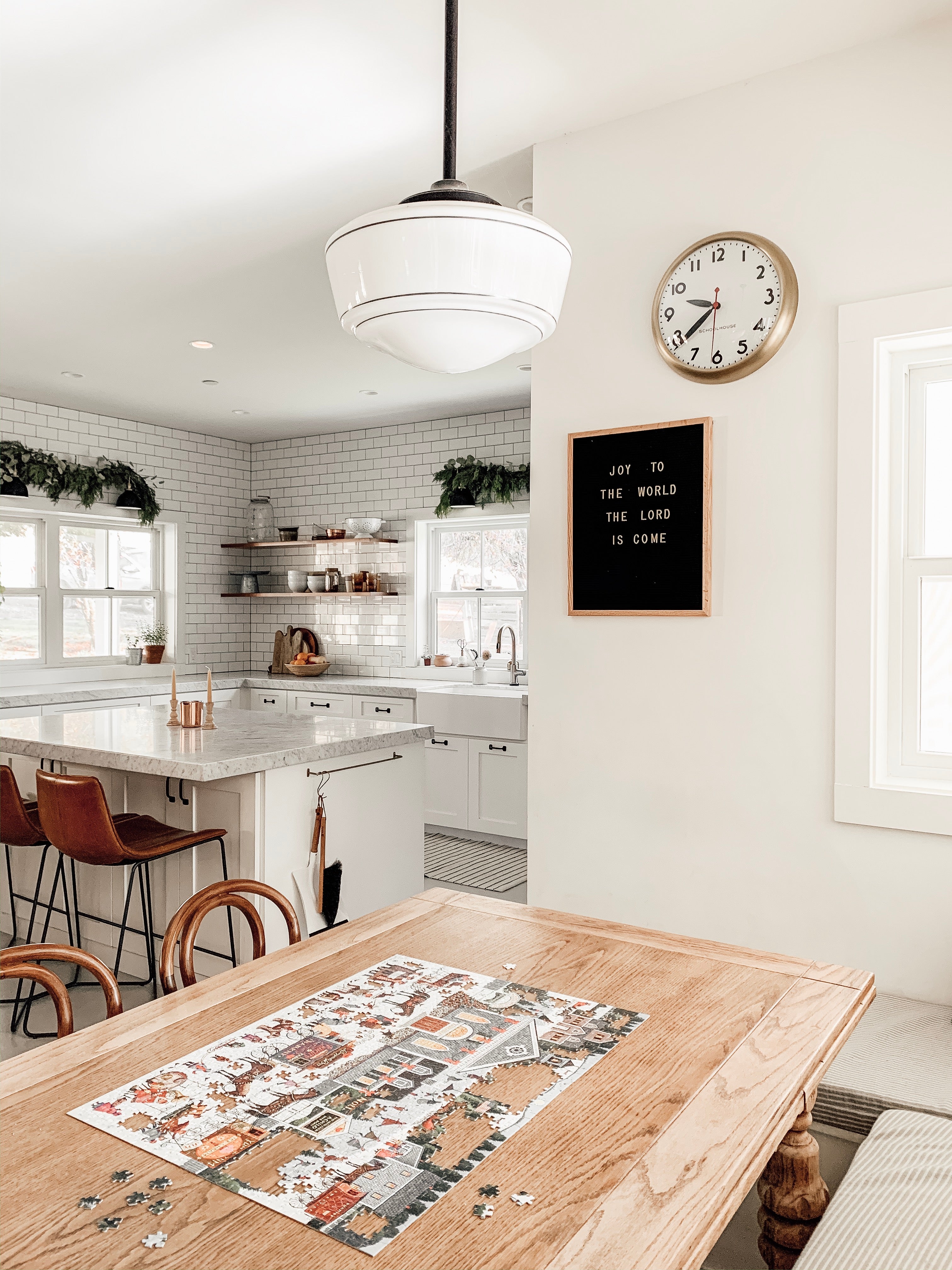 kitchen with a large clock and a table with an unfinished puzzle