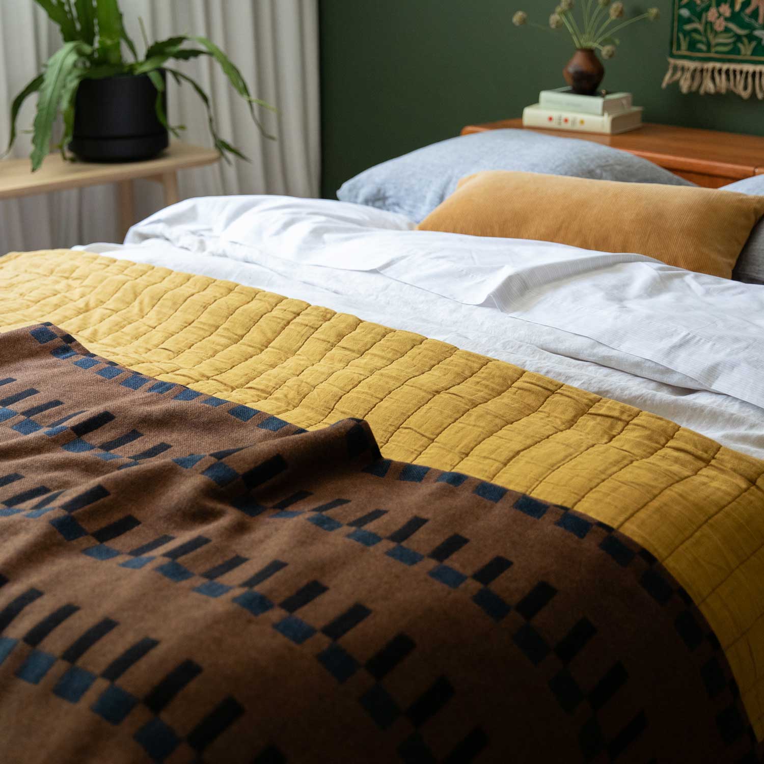 Bed layered with blankets and quilts in various colors.