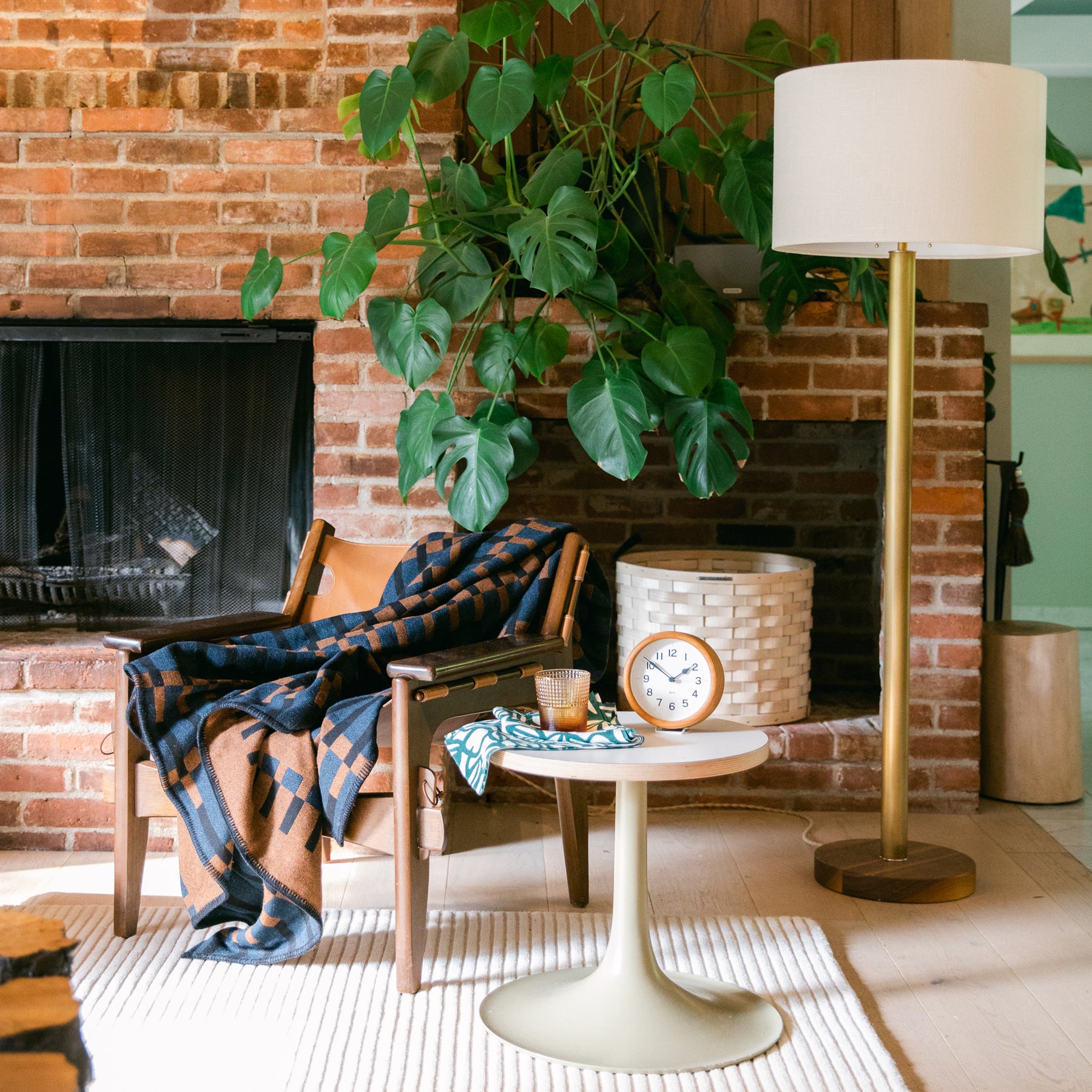 chair and a table in front of a brick wall and gold floor lamp