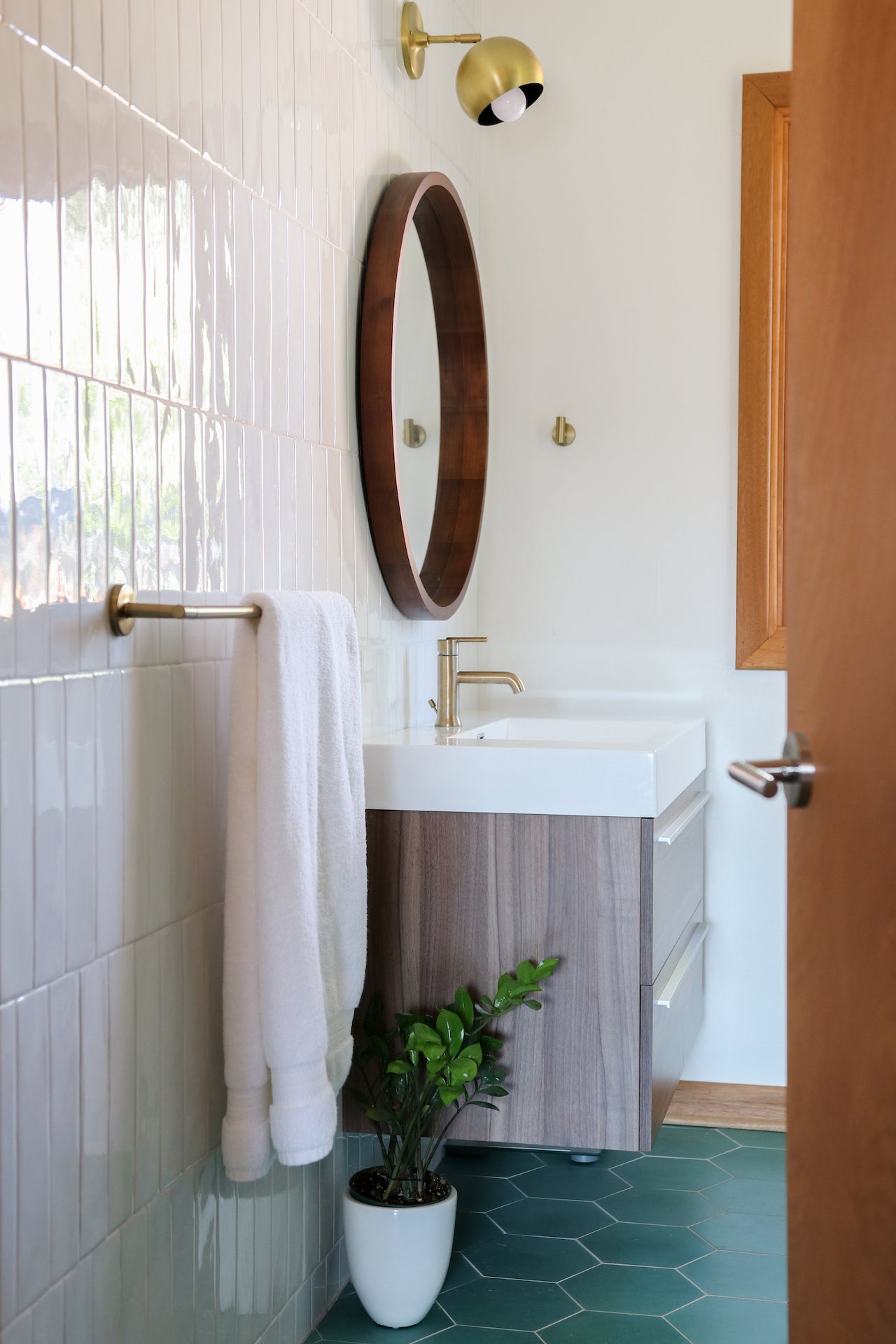 bathroom with a sink and a round mirror and plant on the floor