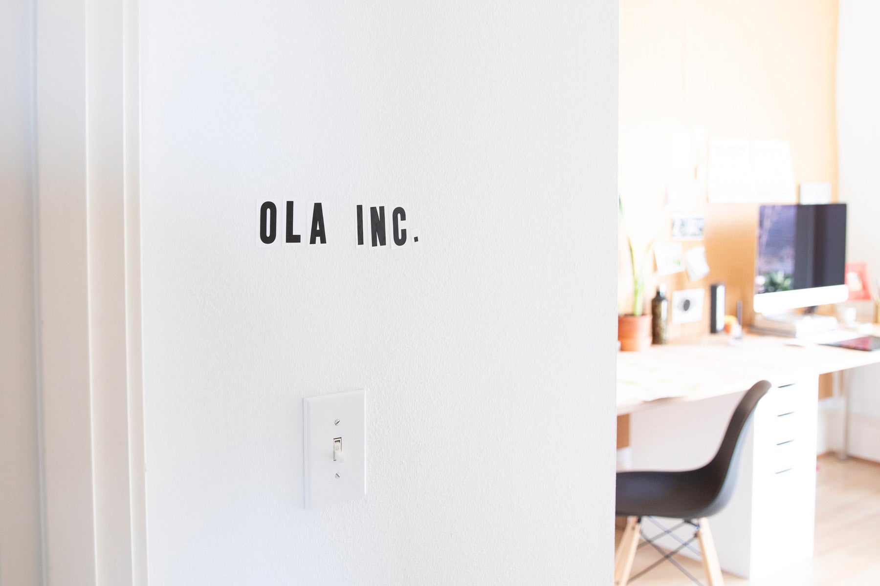 white wall near a desk with computer and chair