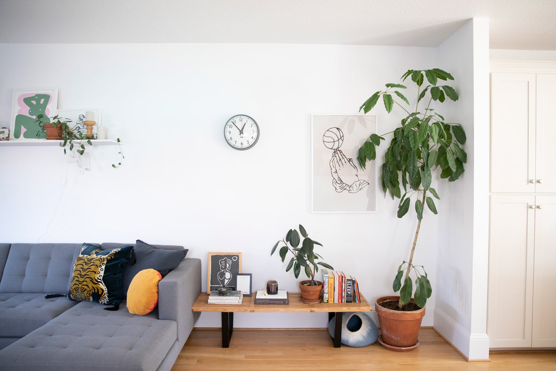living room with a couch and a clock on the wall and a tall plant