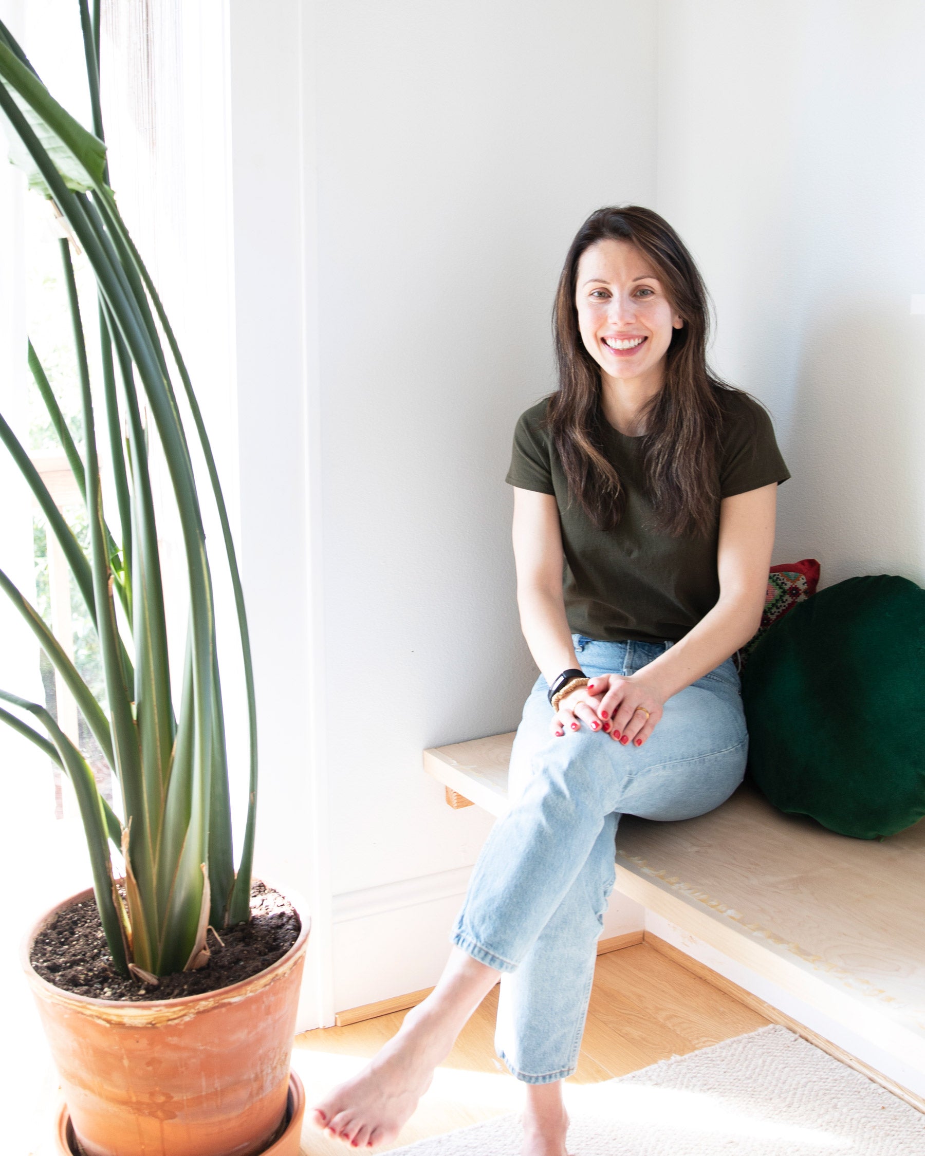 woman sitting on a bench next to a plant