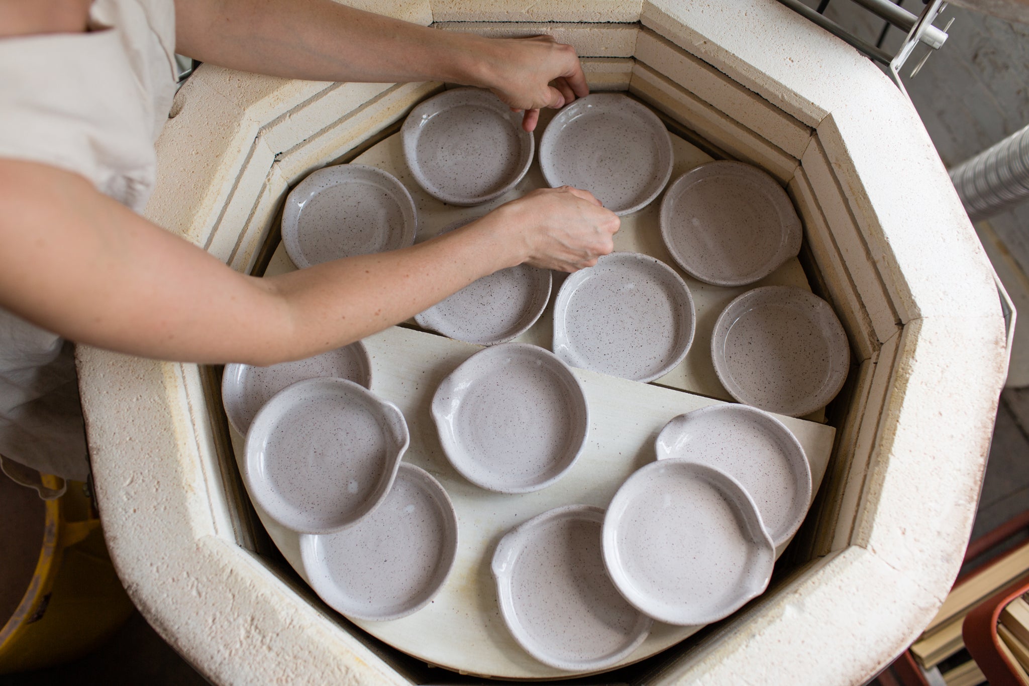 person putting clay items in kiln