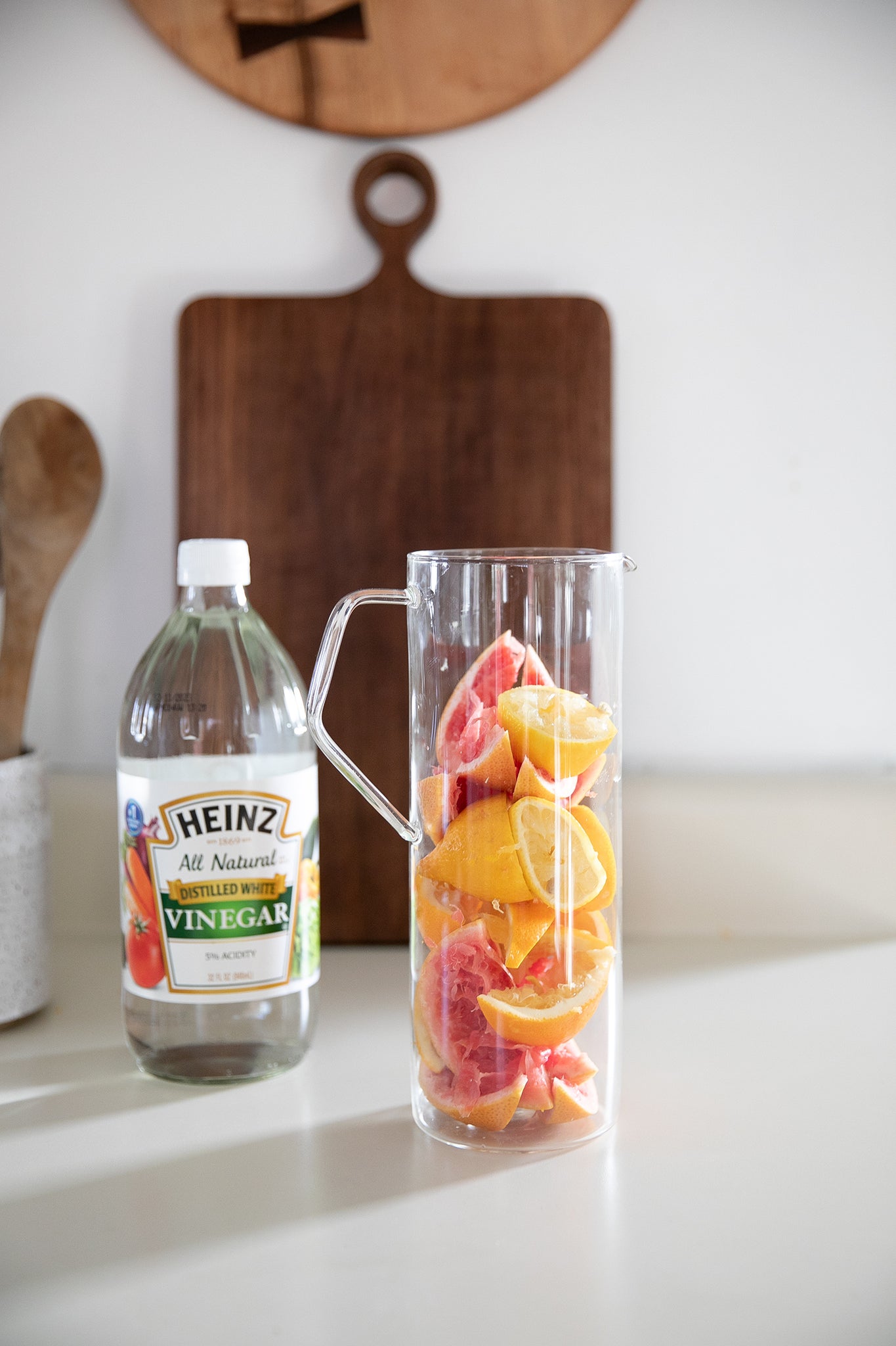 glass bottle or vinegar and a glass with citrus slices in it