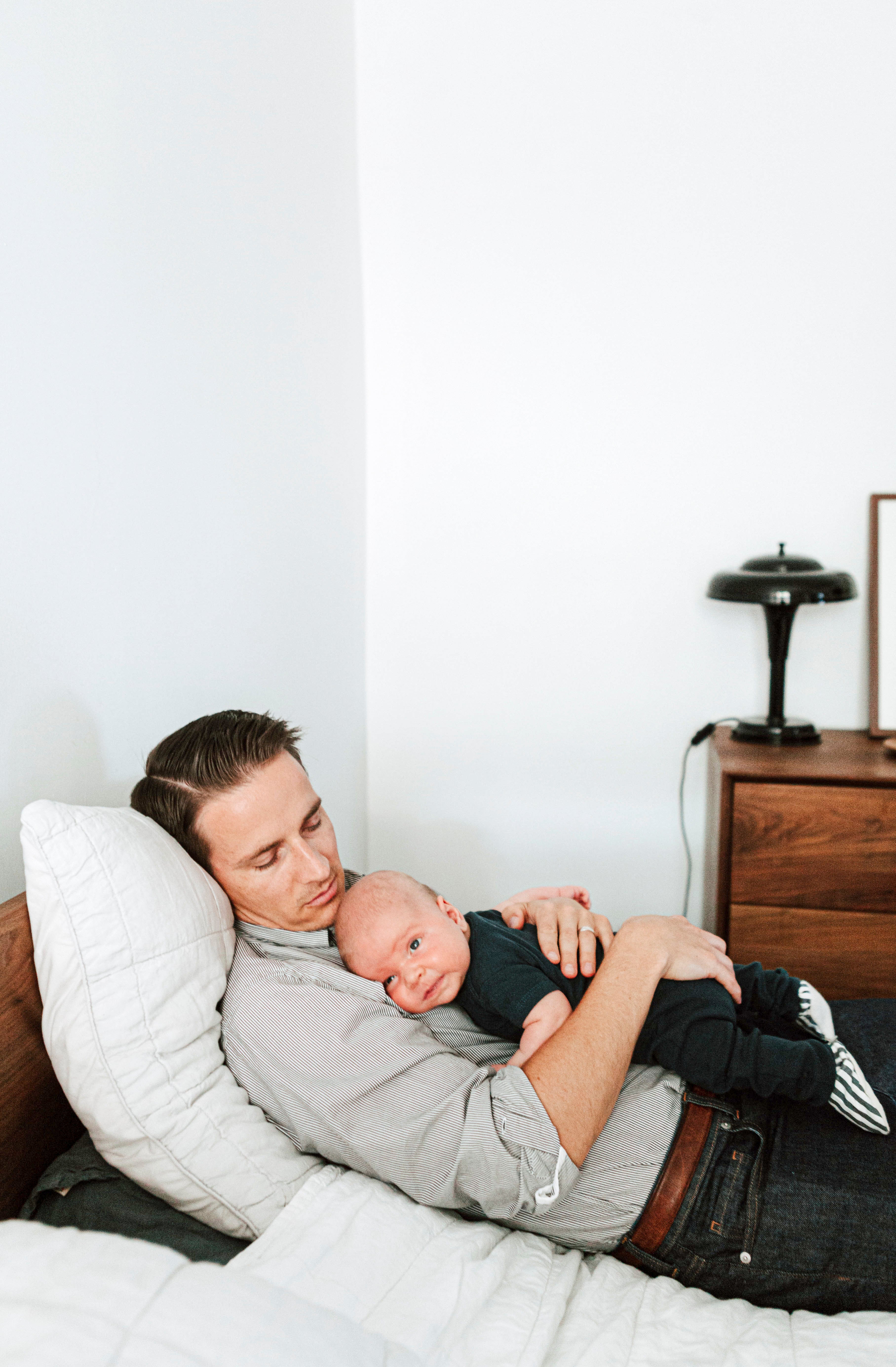 person holding a baby while they lay in bed