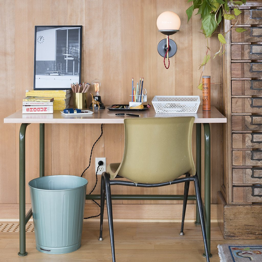 desk with a computer and a chair and trash can