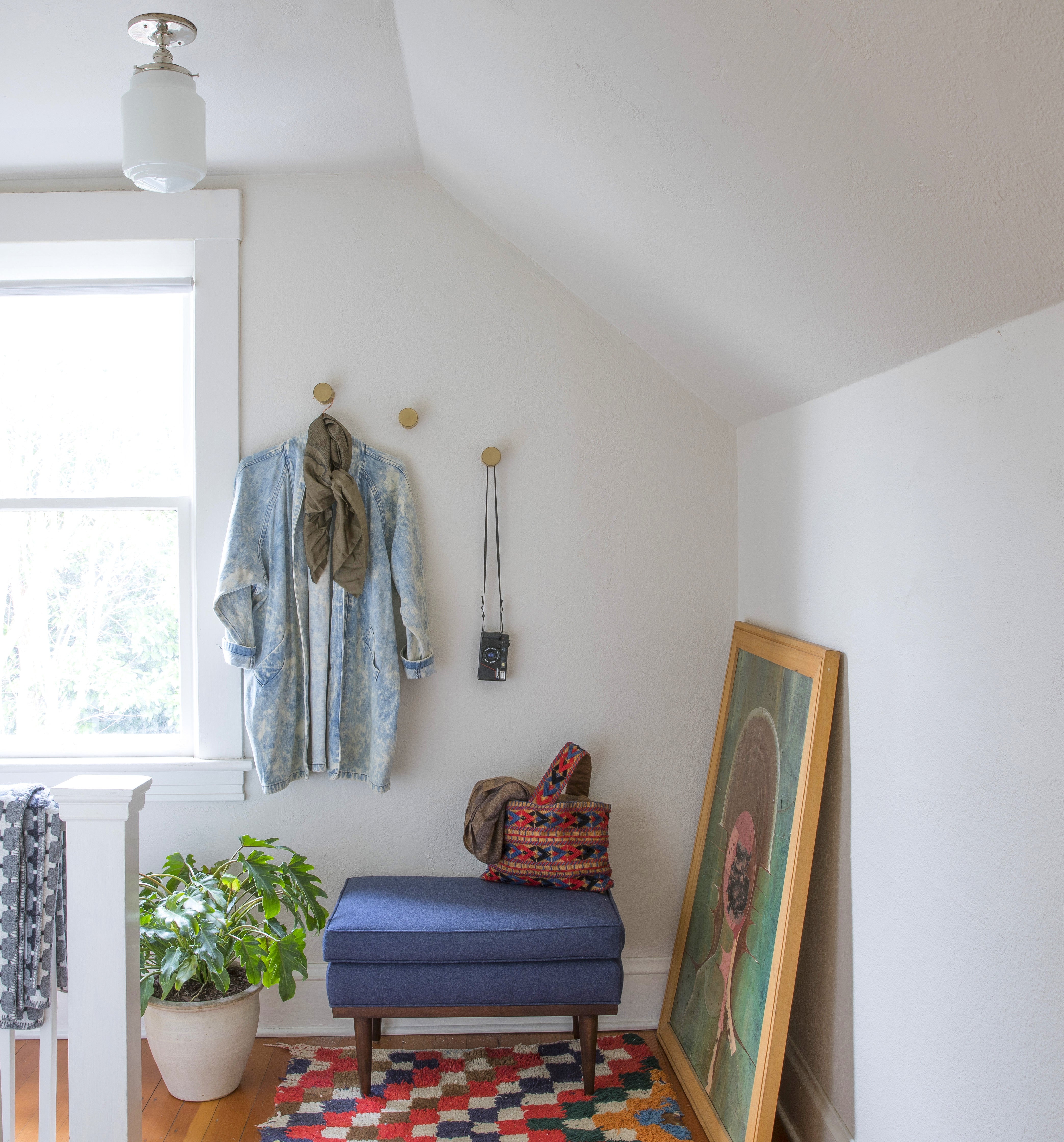 room with a blue chair and a rug and hooks