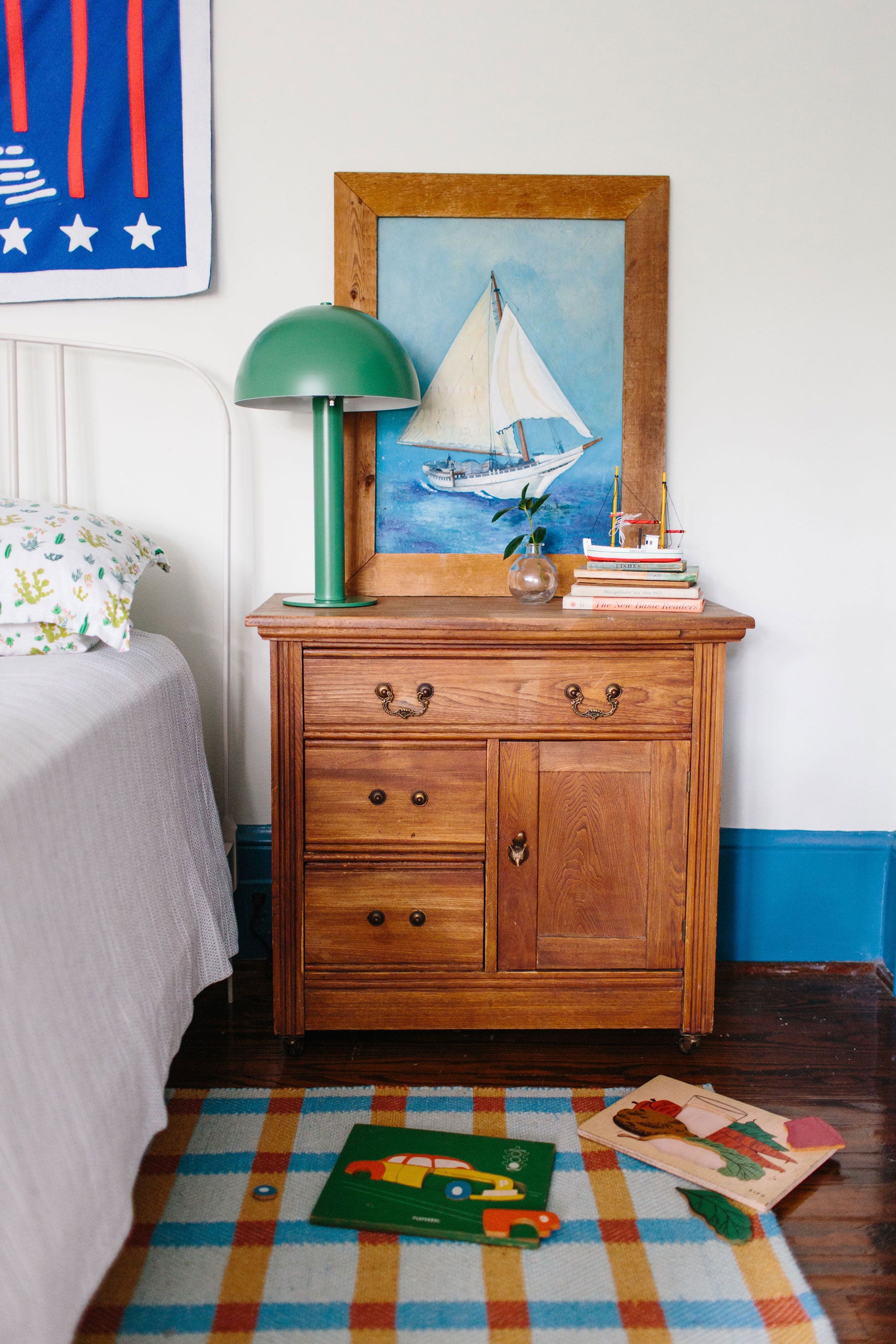 night stand with round green lamp on it and colorful rug on floor