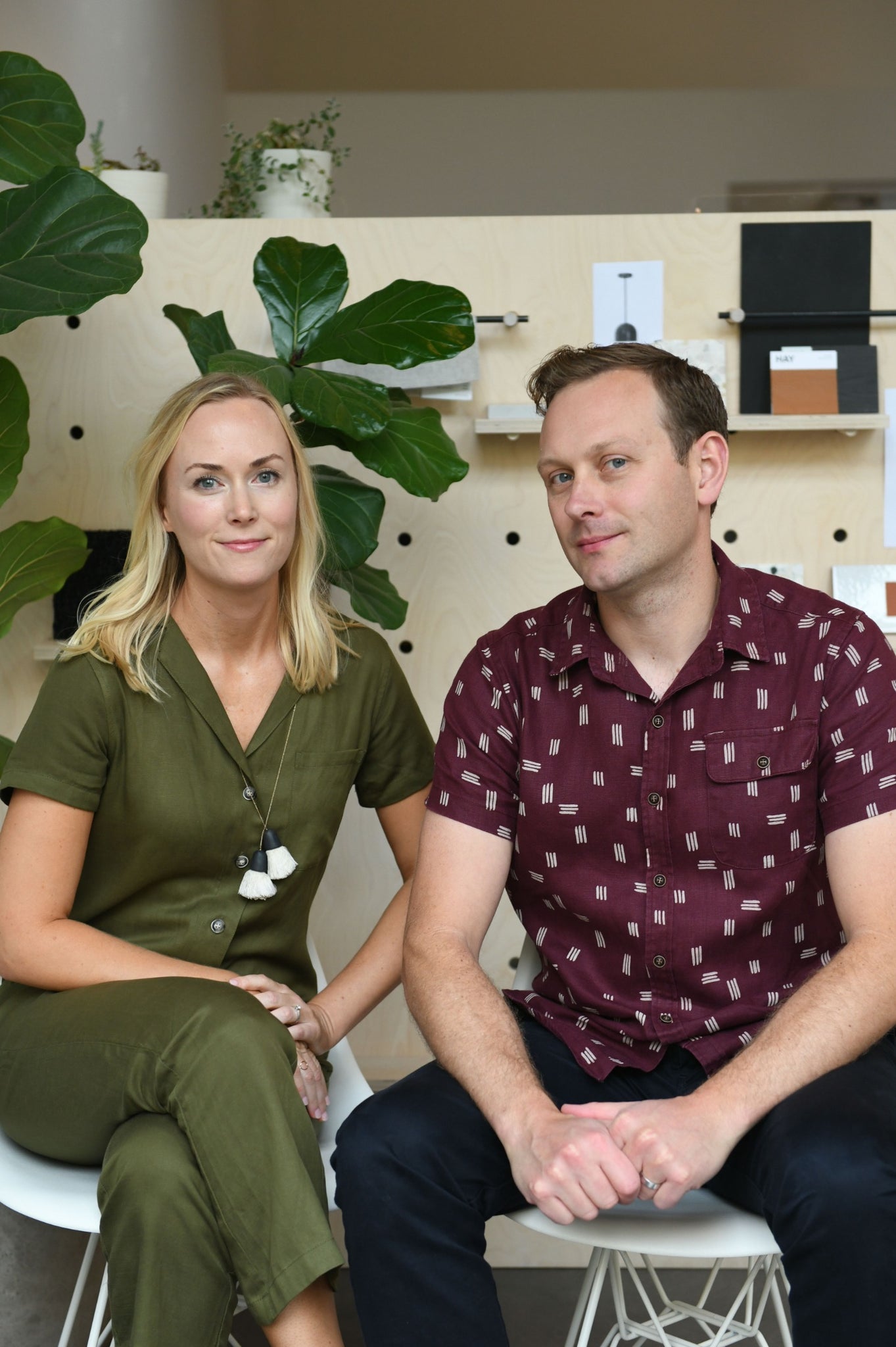 man and woman sitting on a stool in a room with plants