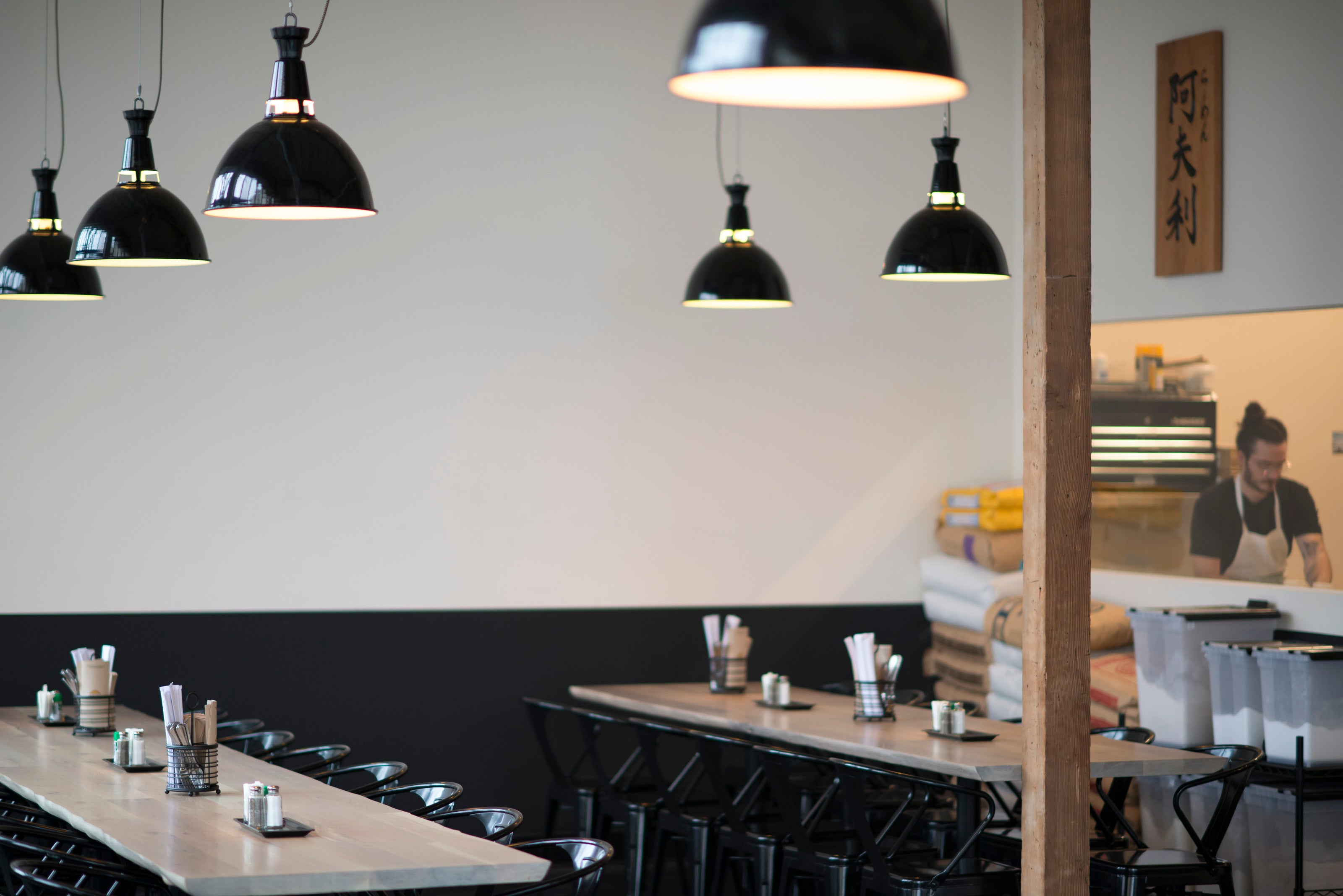 person working in a restaurant and tables and black ceiling light fixtures