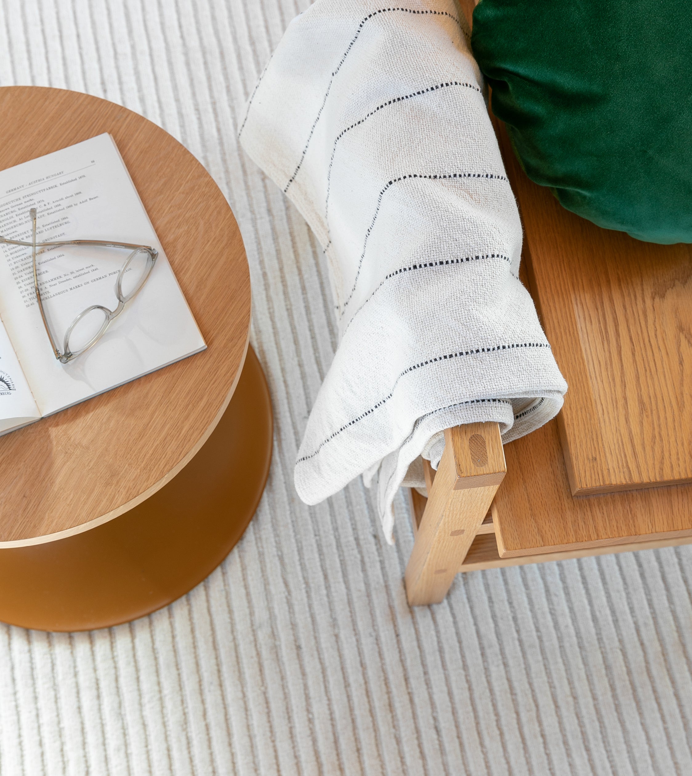 round side table with an open book and reading glasses next to an arm chair