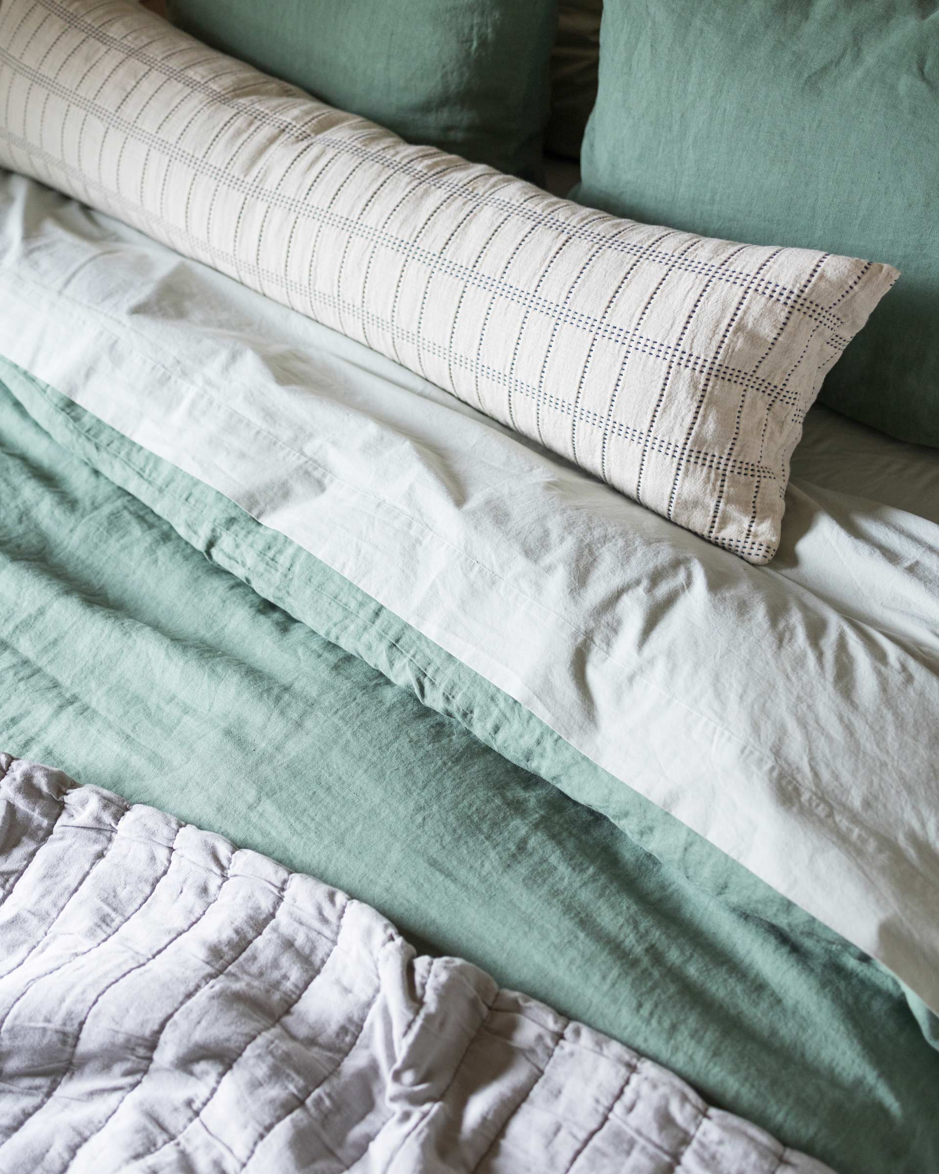 A cozy bed with linen bedding. 