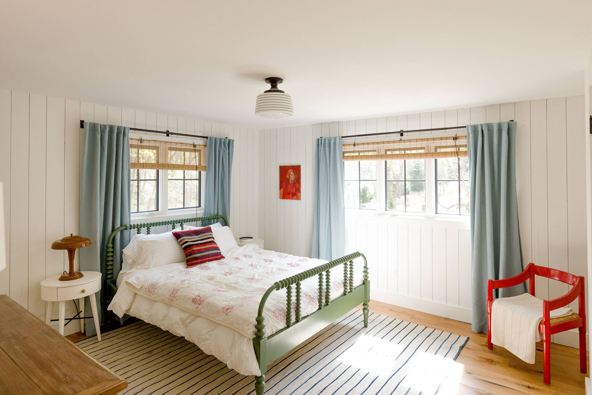 A bedroom with a schoolhouse-style light fixture. 