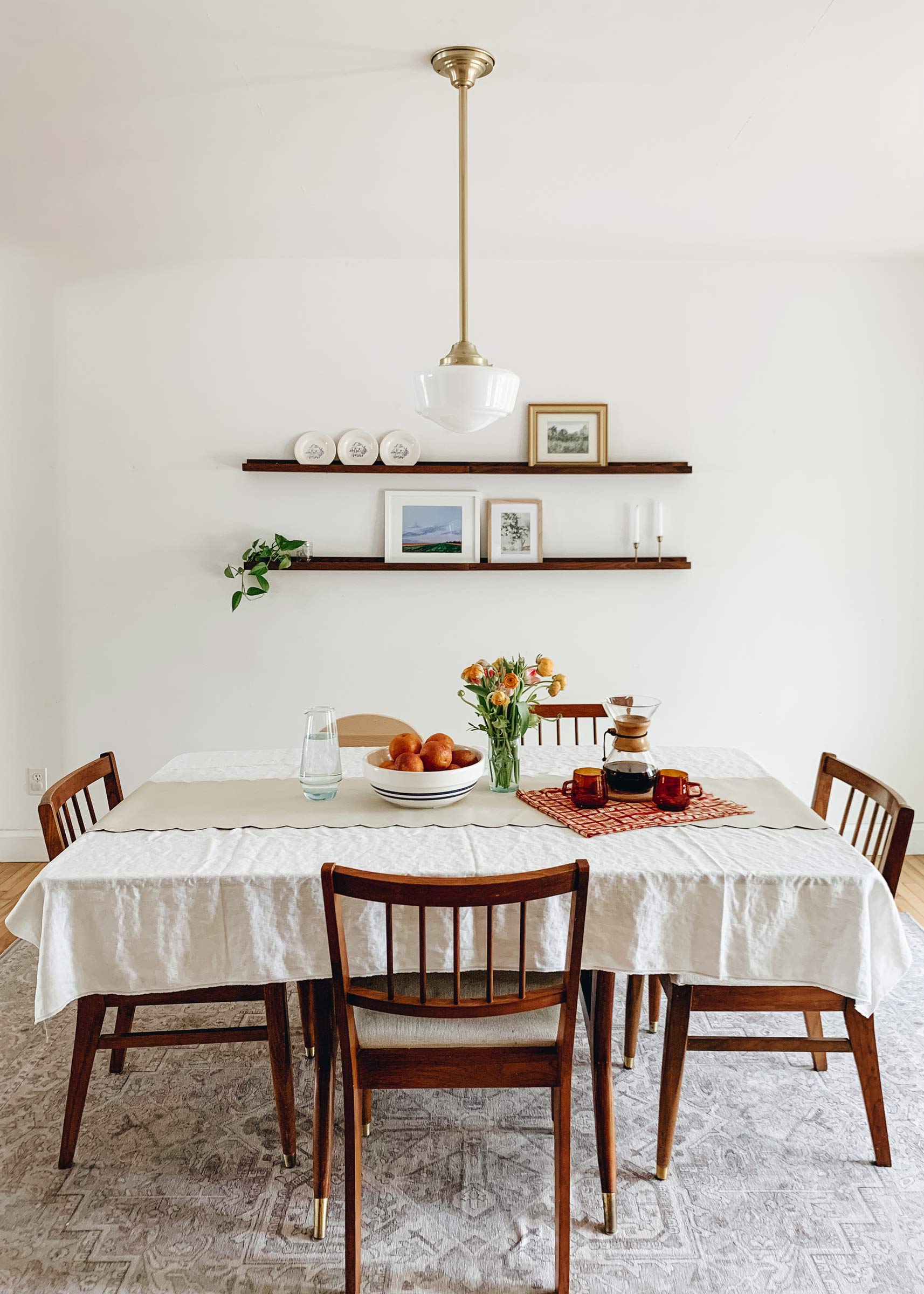 A dining room with a natural brass pendant and schoolhouse-style shade.  