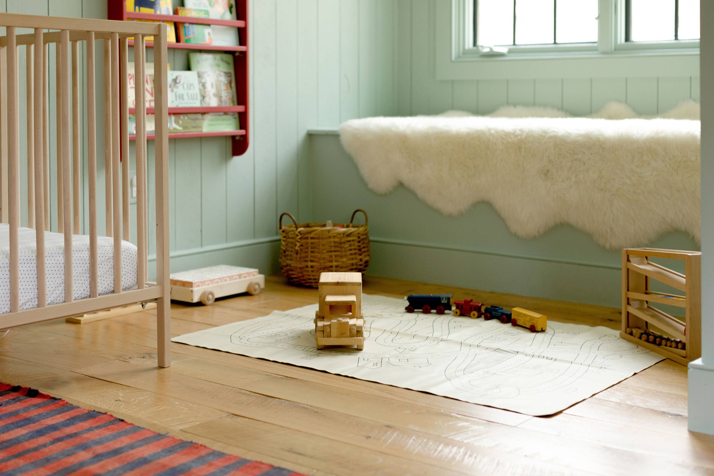 A dreamy nursery with mint green walls and wooden toys on the floor. 