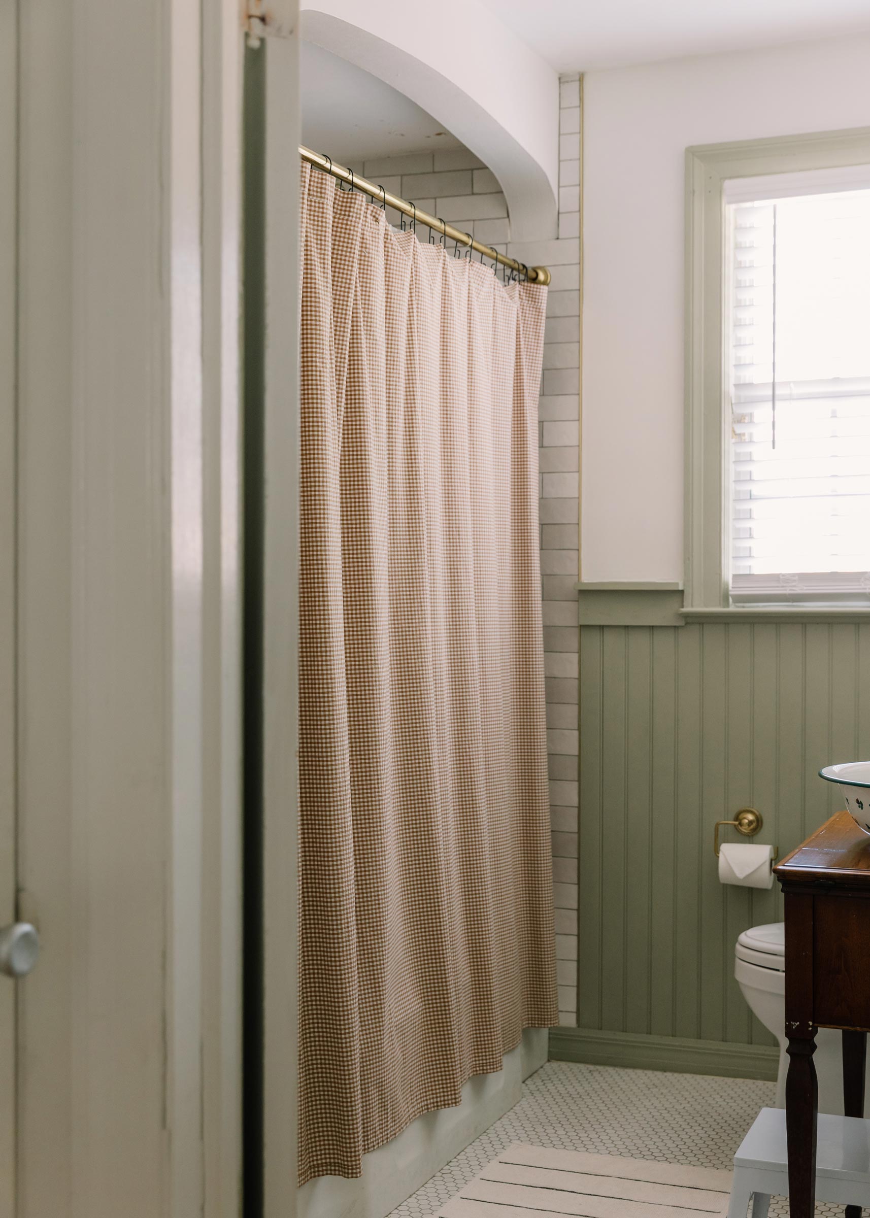 A Gingham shower curtain in a green bathroom. 