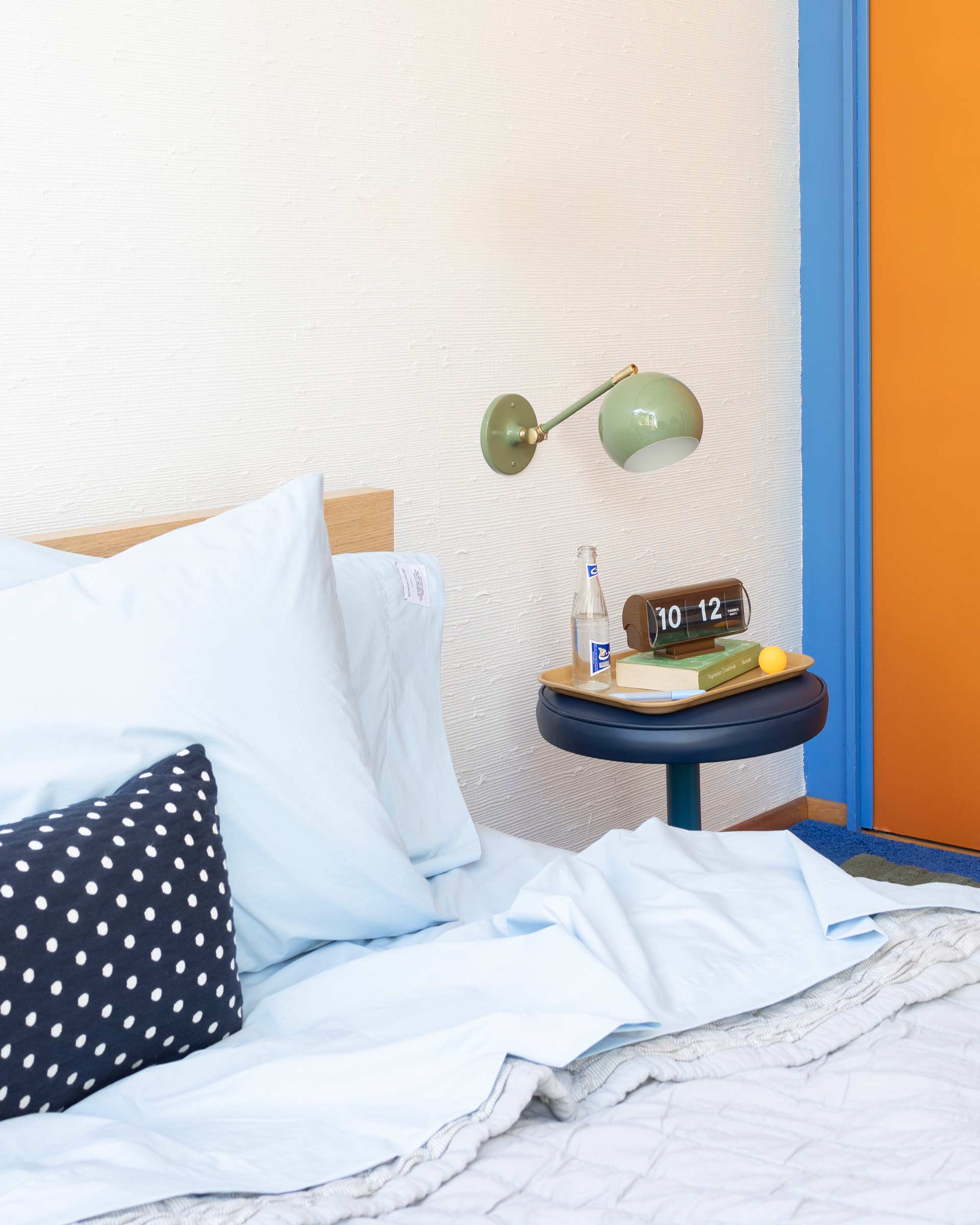 Bed with colorful bedside lamp.