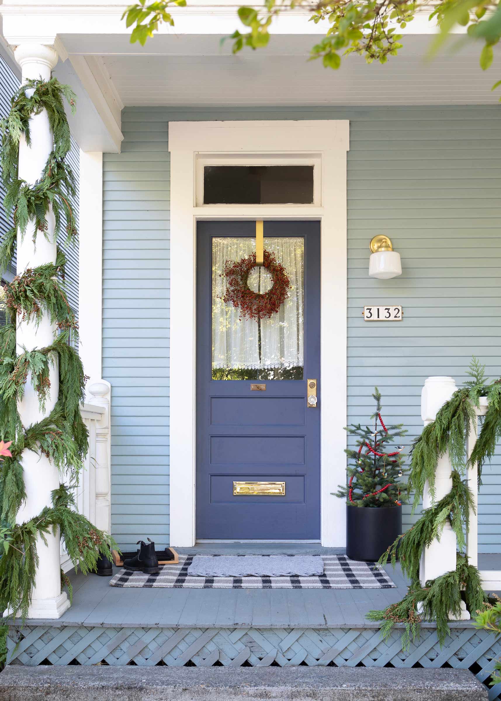 A traditional home exterior with a red berry holiday wreath on a blue door.