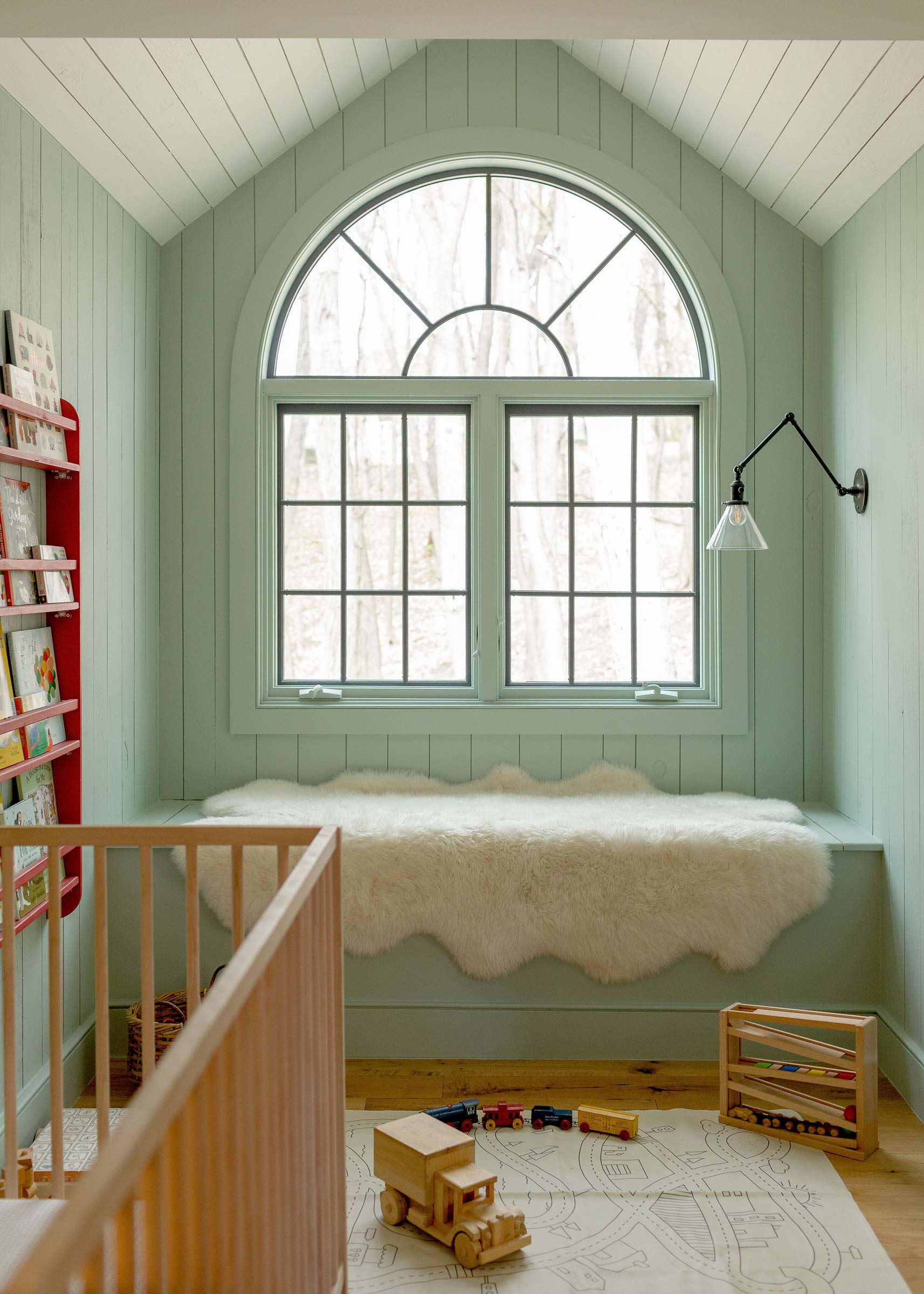 A baby room with a built-in bench by the window. 