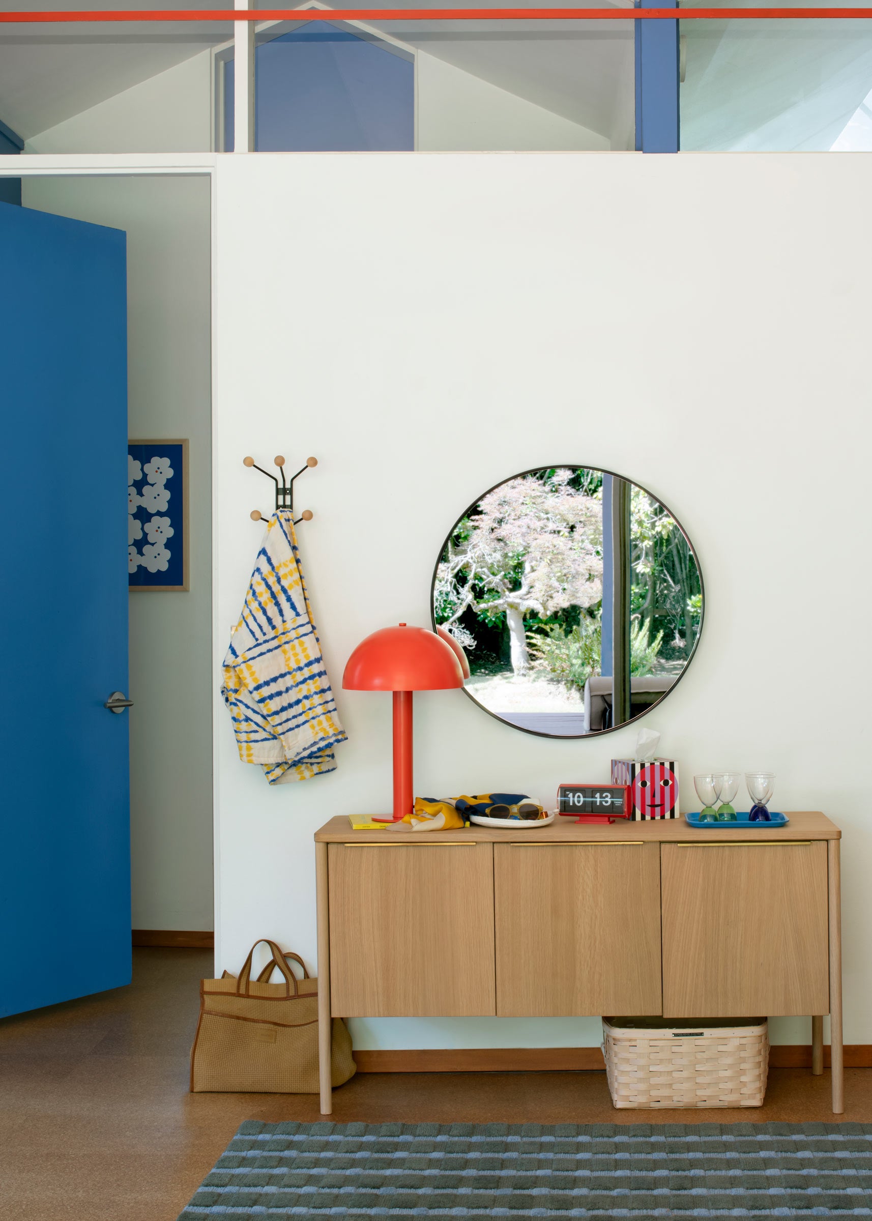 A large round mirror over a sideboard.