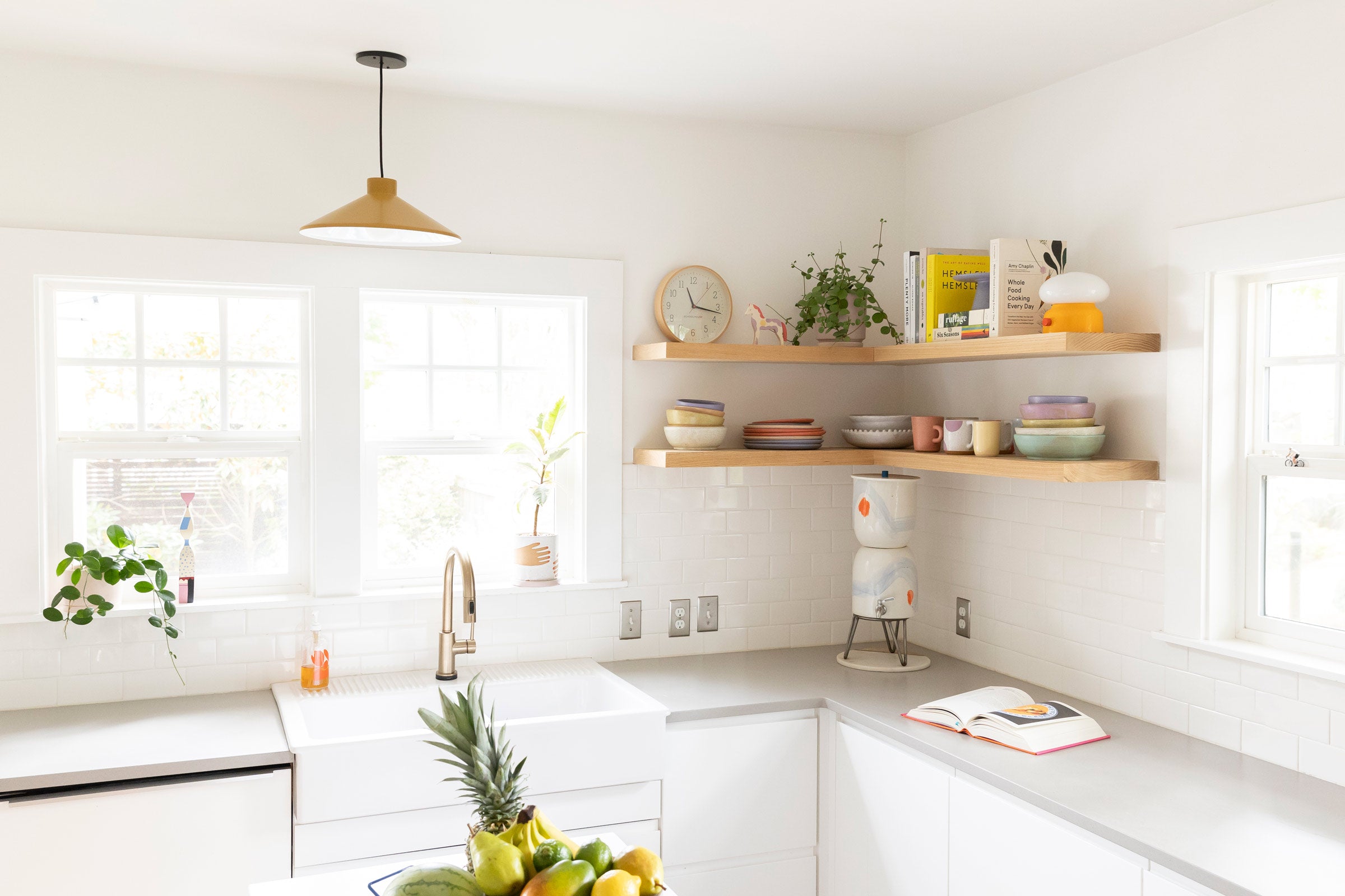 A light-filled kitchen with a dune Gantry Pendant over the sink and wood open shelving.