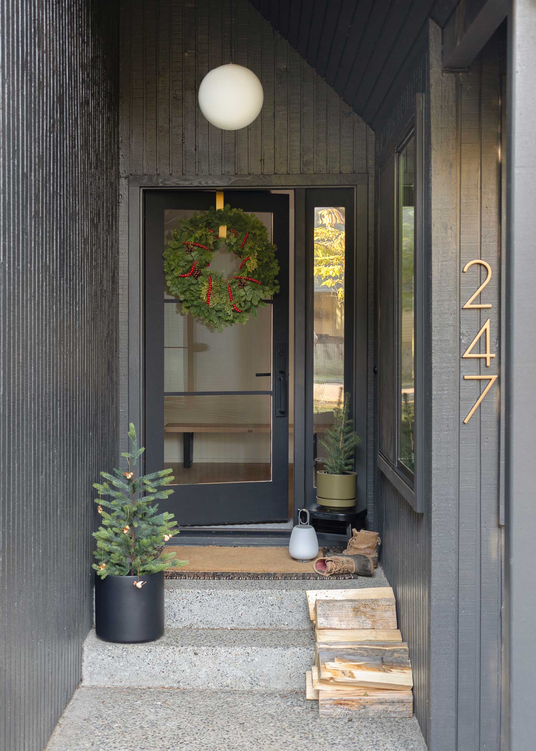 A modern home exterior with a globe pendant and holiday wreath.