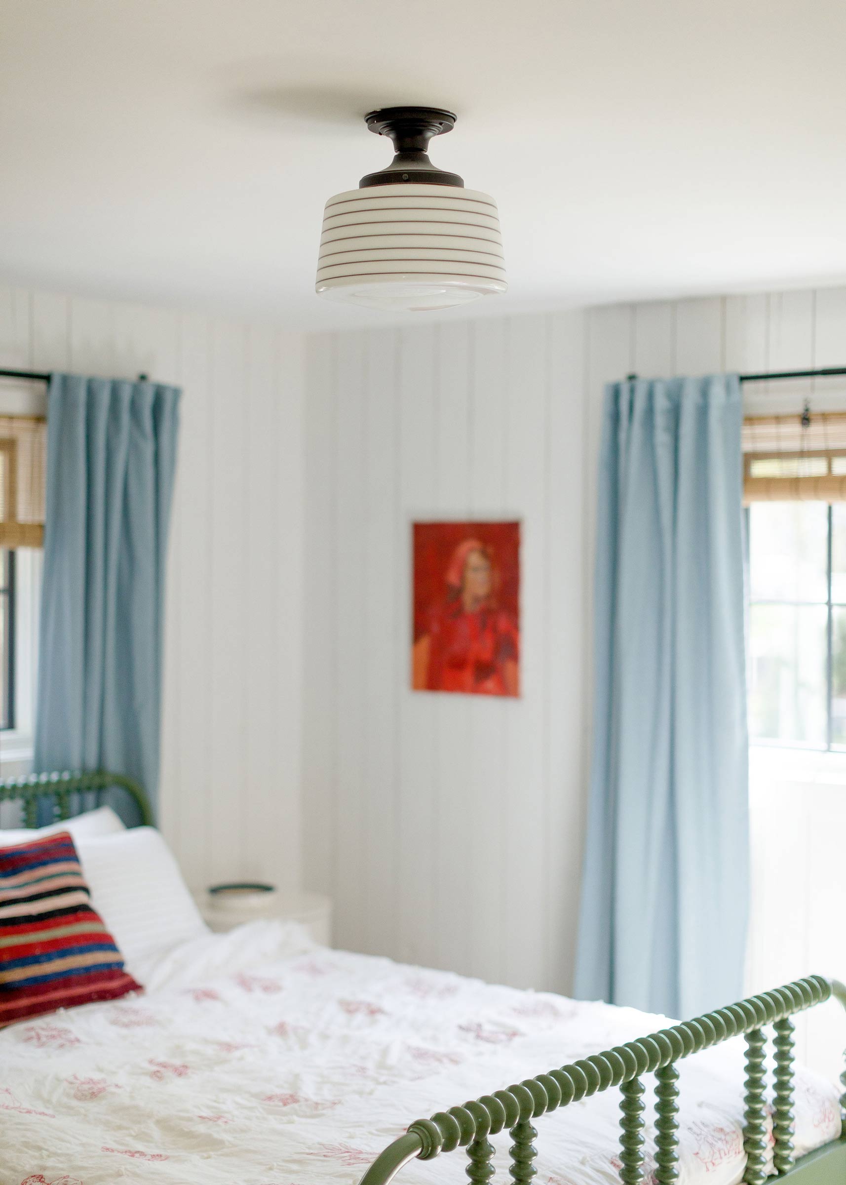 A schoolhouse-style light fixture in a modern bedroom. 